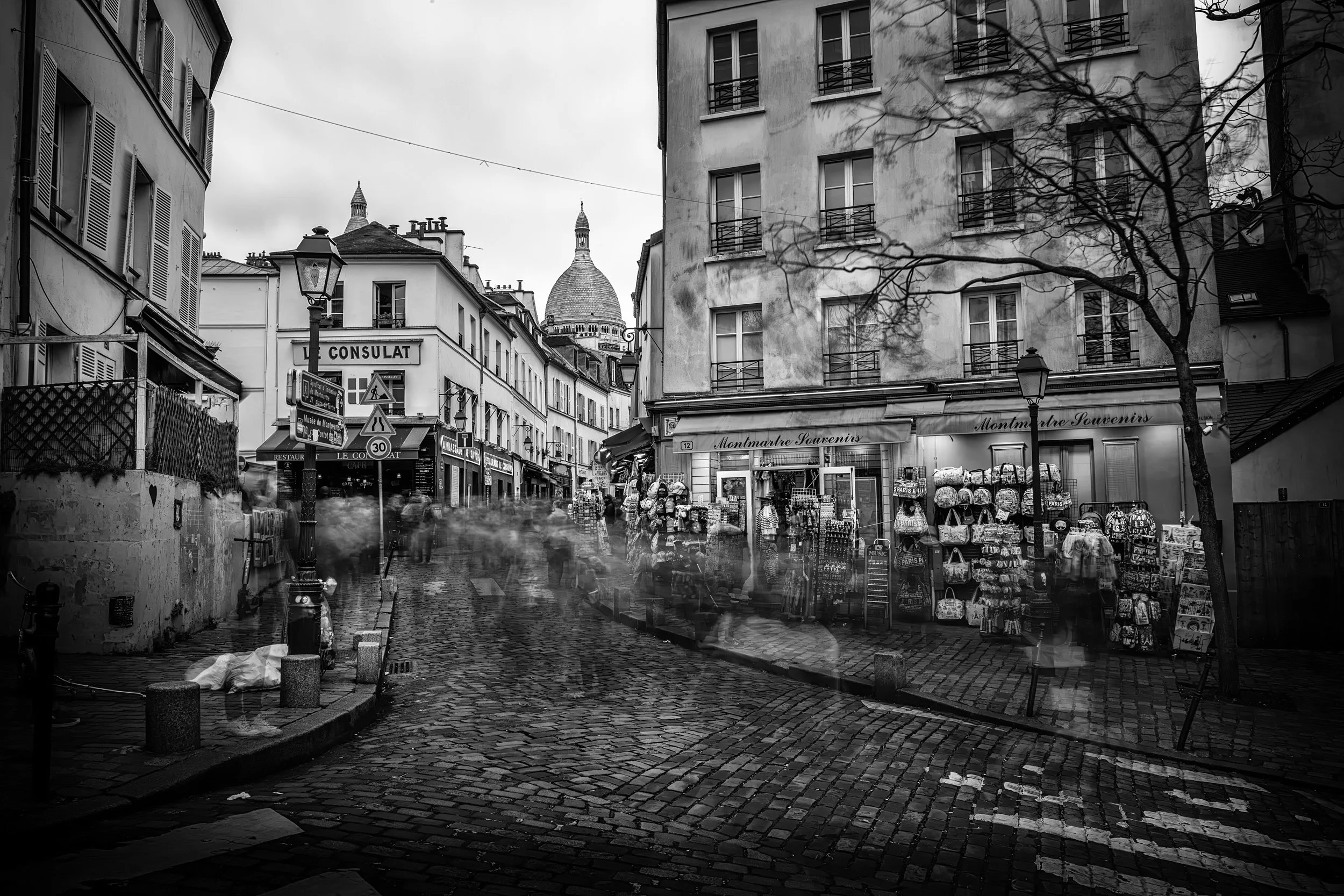 Montmartre in Motion

 

  A Montmartre street in Paris with cobblestones, storefronts, pedestrians, and the dome of Sacre-Coeur above the rooftops. The neighborhood remains one of the city’s best-known hilltop districts. 