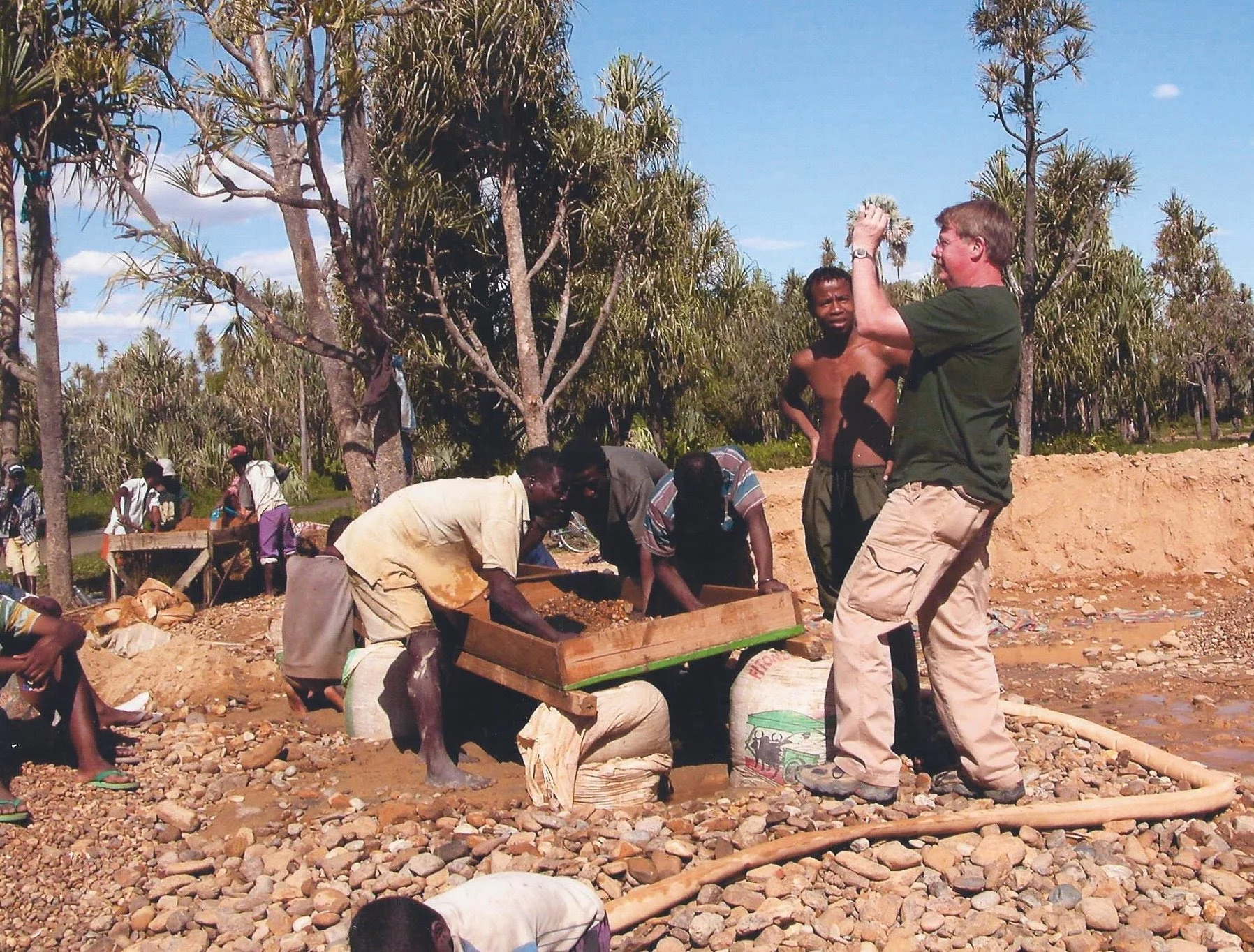 PHOTO OF A GROUP OF AFRICAN SAPPHIRE MINERS AND A SUNBURNED WHITE GEM BUYER.