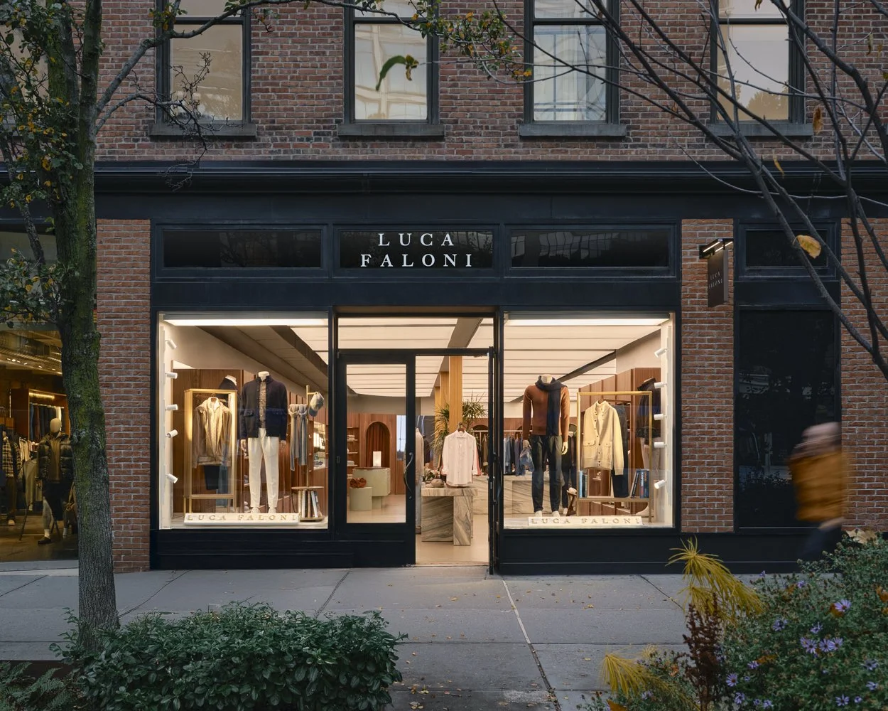 Exterior view of a clothing boutique named LUCA FALONI with large glass windows showing mannequins dressed in casual and formal clothing, and interior displays of stylish apparel and decor inside.