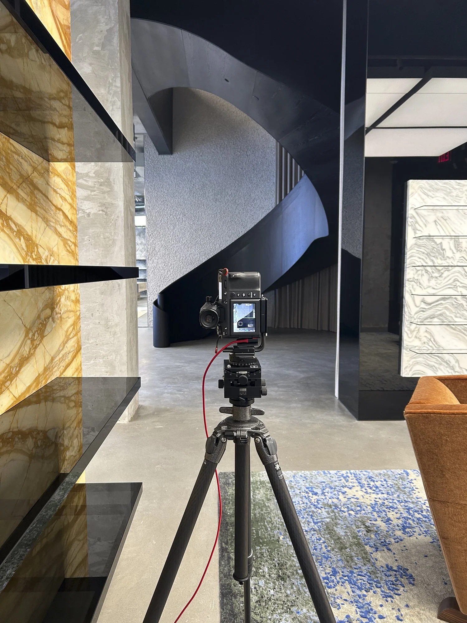 Tripod camera setup photographing the sculptural staircase inside Saint Laurent’s flagship retail interior