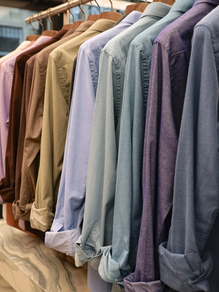 A display of multicolored button-up shirts hanging on a rack in a store.