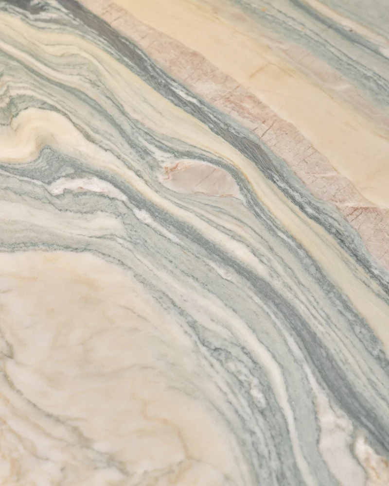 Close-up view of a marble surface with swirling gray, cream, and pinkish tones.