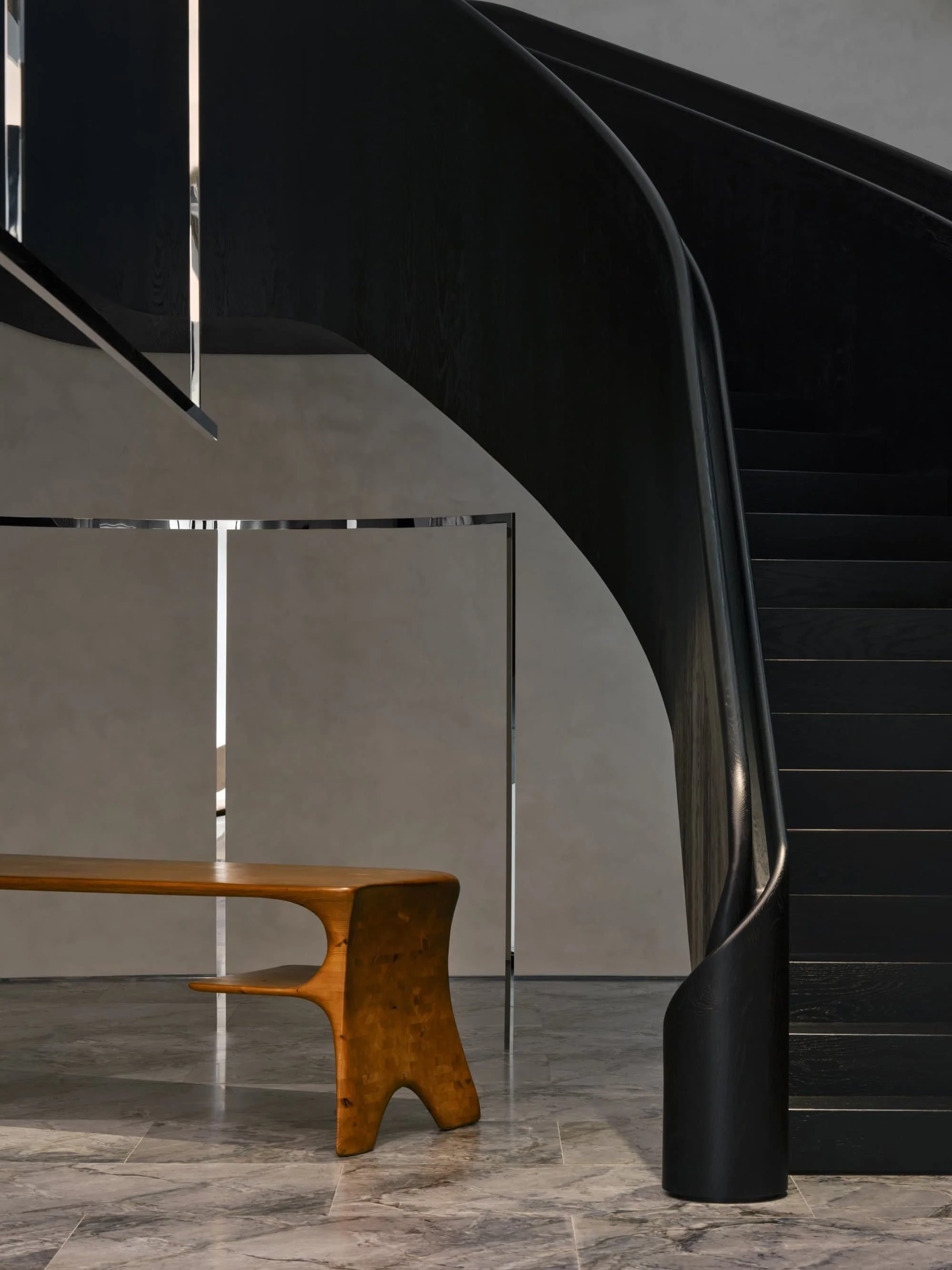Saint Laurent curved black staircase with sculptural wood stool