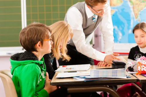 Image of group tuition with teacher helping young students with their maths work