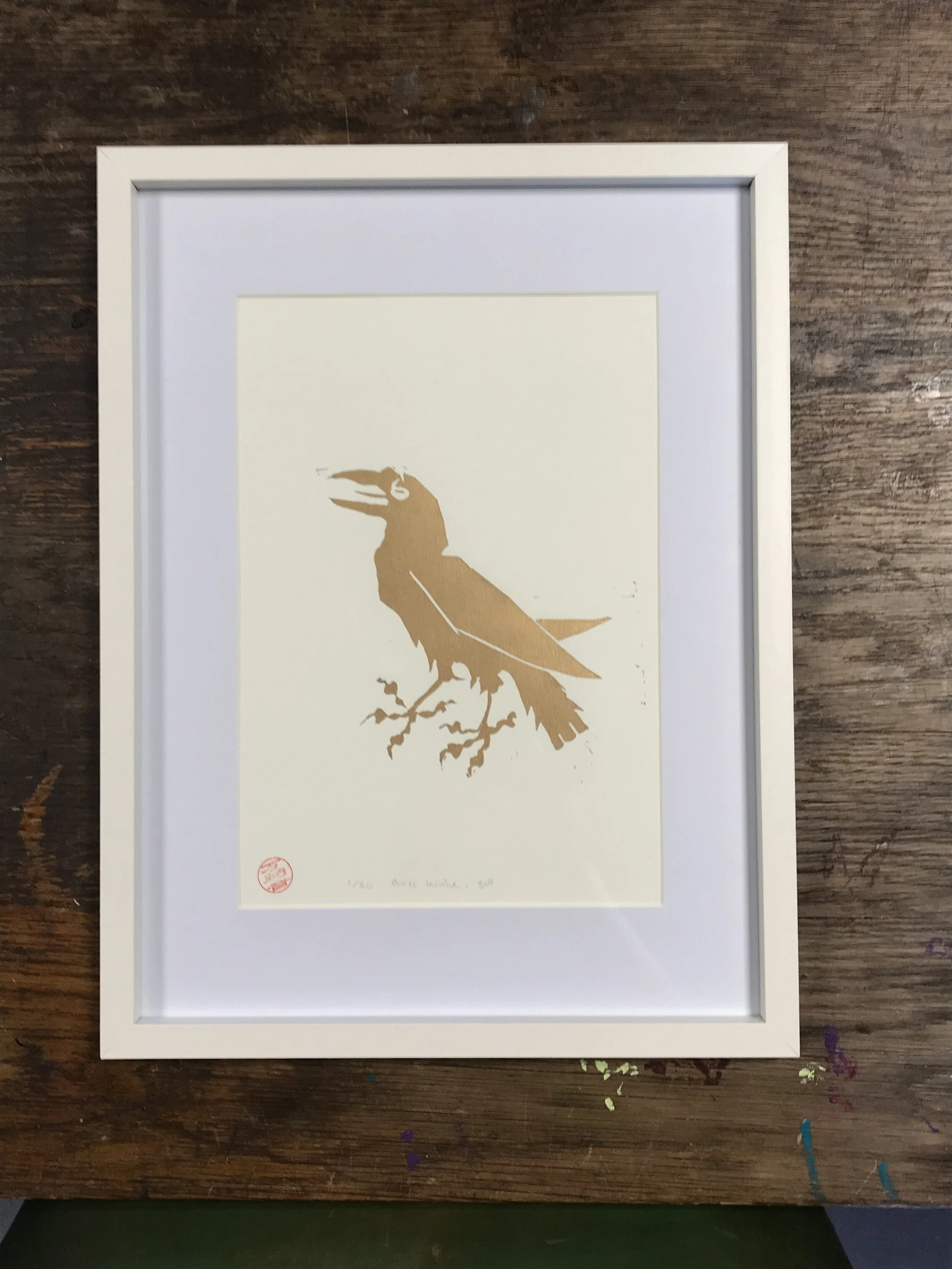 Bare kråke trykket i gull på hvitt kunstpapir, innrammet 