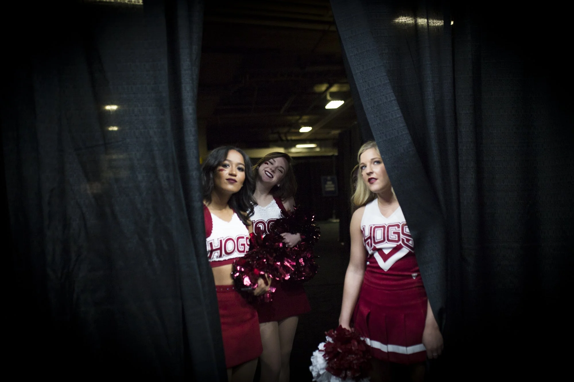 Arkansas Razorbacks cheerleaders peak through a curtain leading to the court during the Southeastern Conference Men's Basketball Tournament, Thursday, March 8, 2018 at Scottrade Center in St. Louis, Mo.