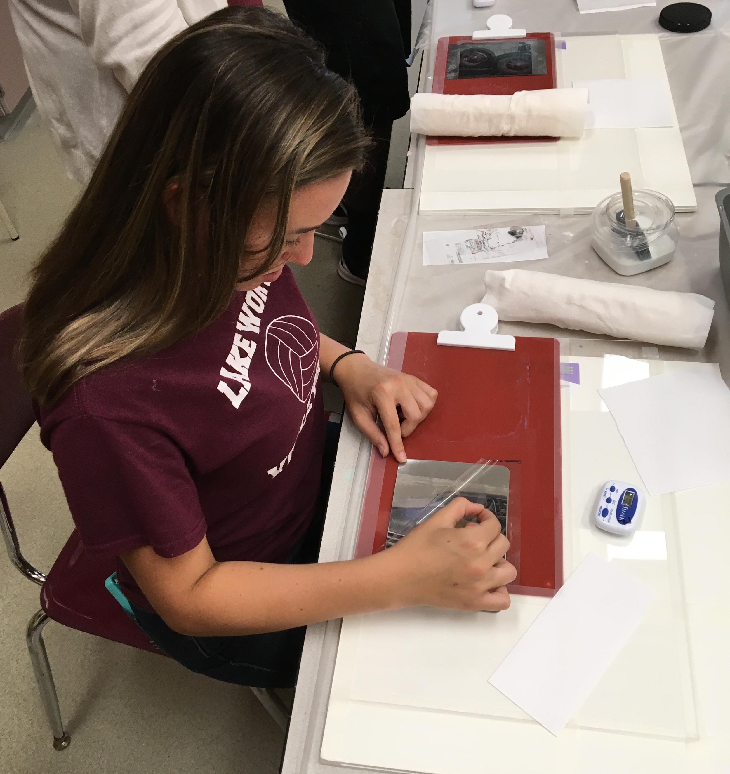 Student pulling backing off transfer to see image on metal.