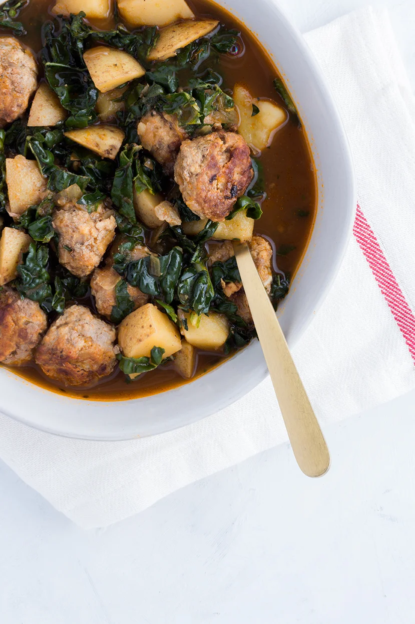 Come on and get cozy with this bowl of Lamb Meatball Stew featuring potatoes, kale and some smokey Spanish paprika.