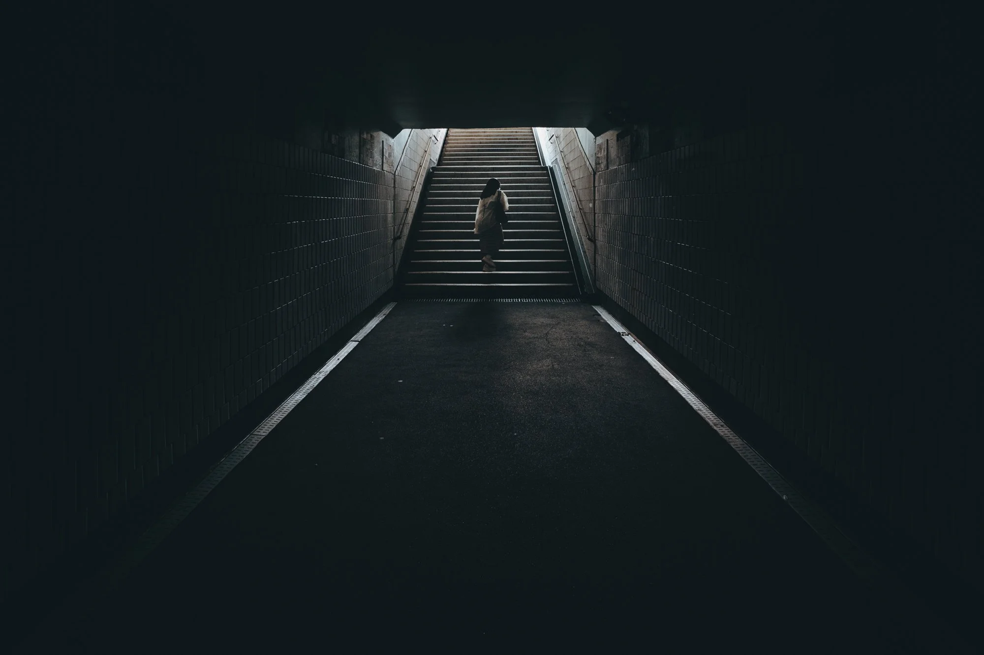 A woman ascending up the staircase from a dark underpass in Seoul, South Korea