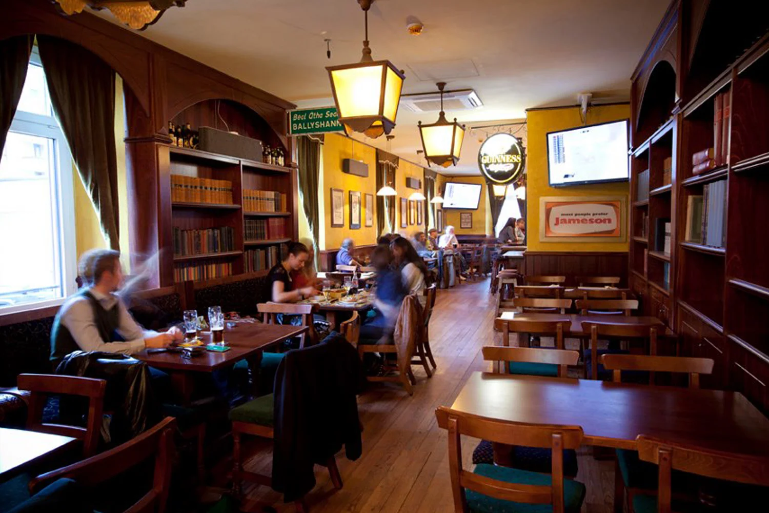 The Trinity Irish Pub Design Interior - yellow walls with soft lighting and wooden furniture.