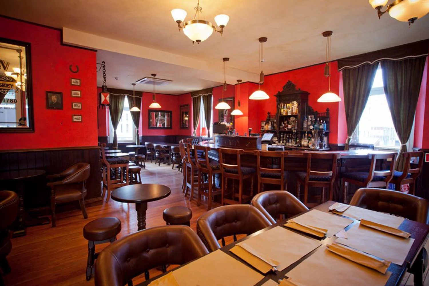 The Trinity Irish Pub design - interior design seating area with red walls and wooden furniture. 
