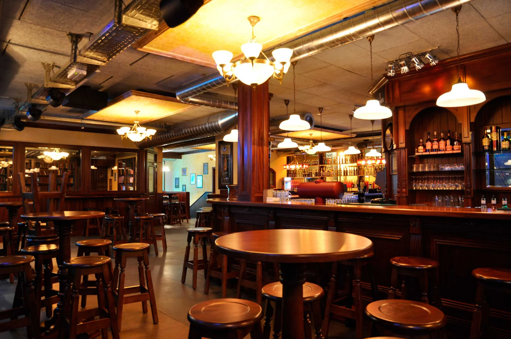 Peggy O'Neil's Irish pub design - interior view of wooden bar and high wooden tables with wooden stools