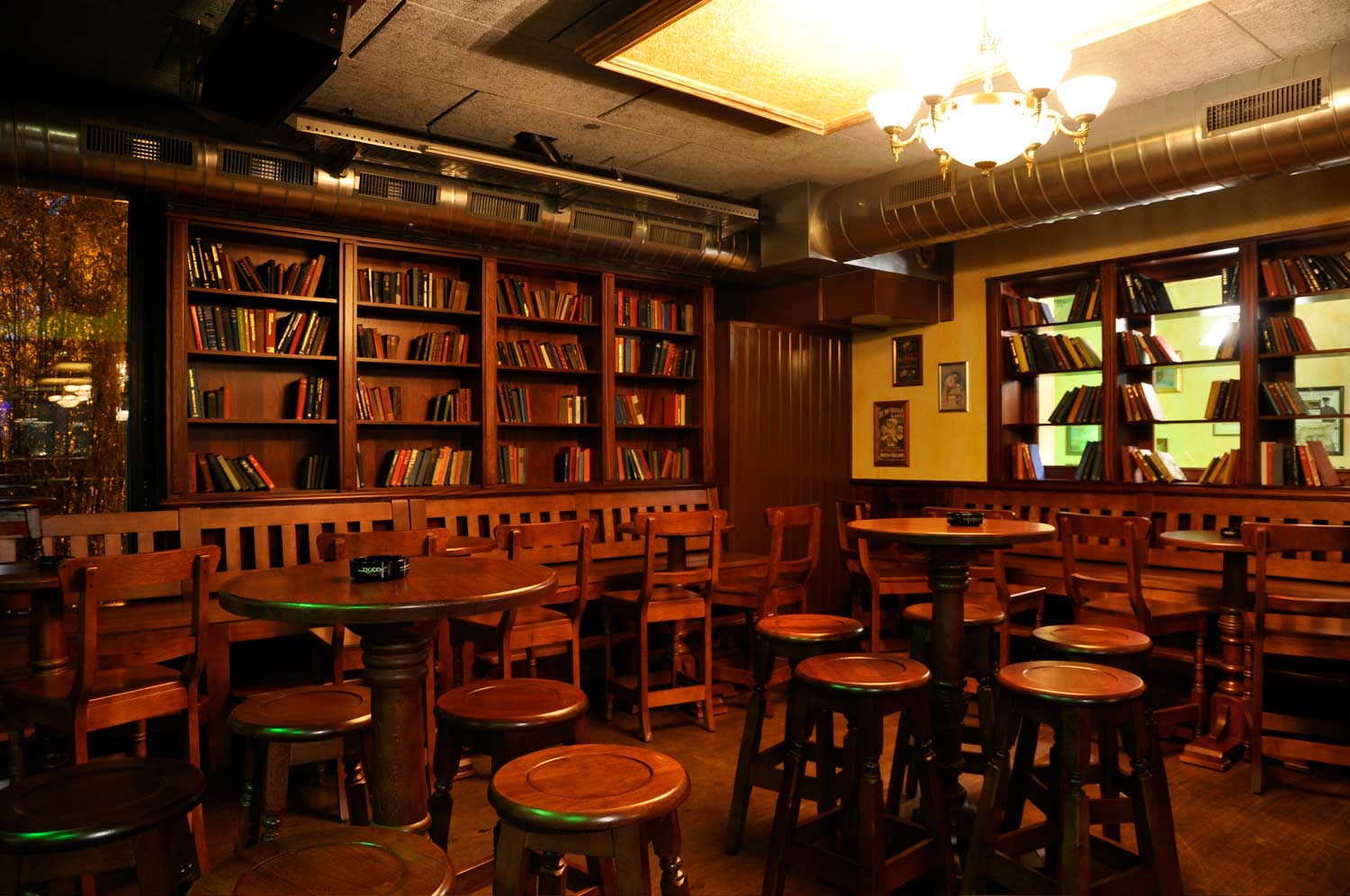 Peggy O'Neil's authentic Irish pub design - interior seating, low wooden tables and wooden chairs with books on wooden shelving