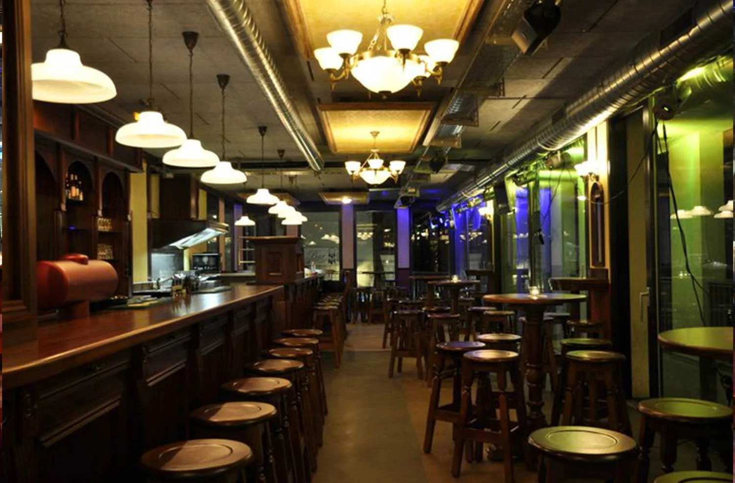 Peggy O'Neil's Irish bar design - interior wooden bar with stools lined up and high wooden tables with stools&nbsp;