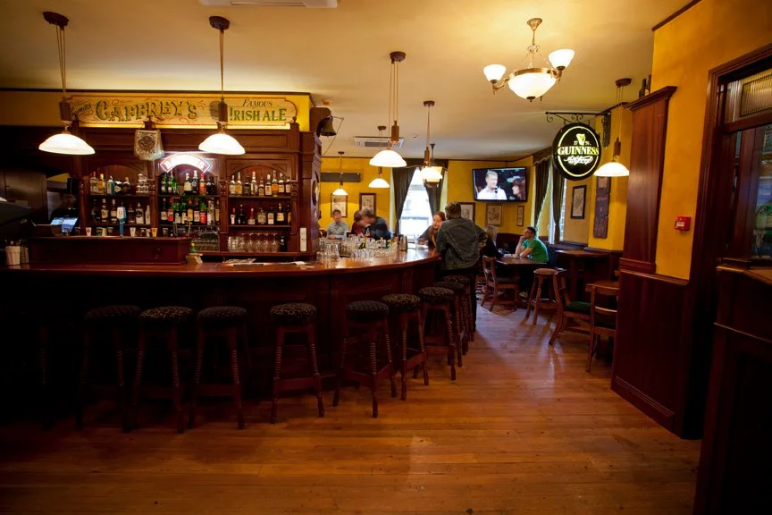 Trinity Irish Pub design - interior view of curved wooden bar and stools