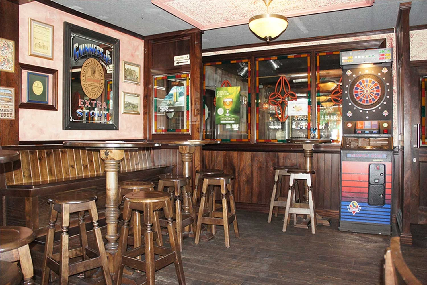 Duffy O'Toole's Irish pub design - interior view of lightwood high tables and stools and traditional Irish mirrors with Guinness logo and Celtic emblems.&nbsp;