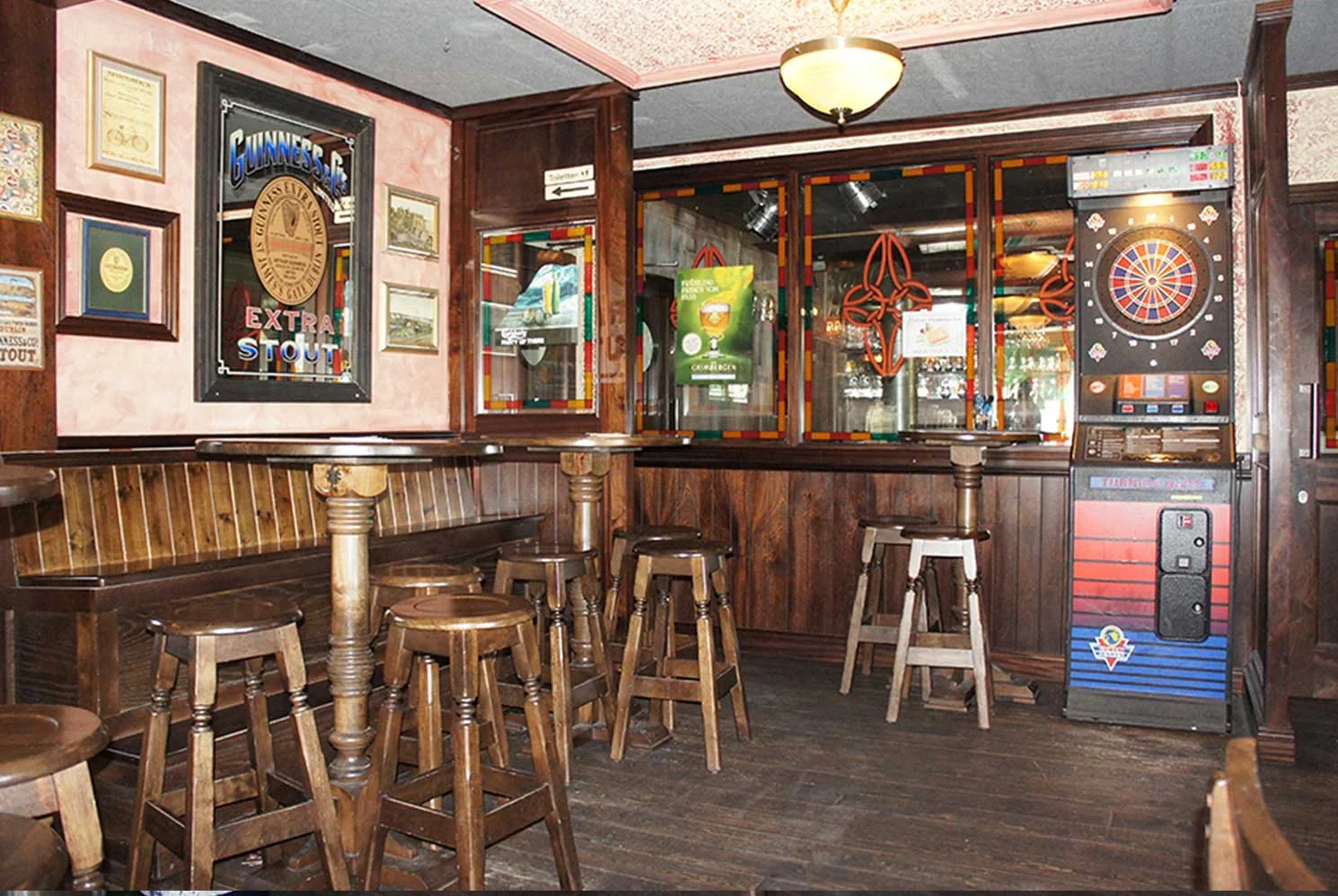Duffy O'Toole's Irish pub design - interior view of lightwood high tables and stools and traditional Irish mirrors with Guinness logo and Celtic emblems.&nbsp;