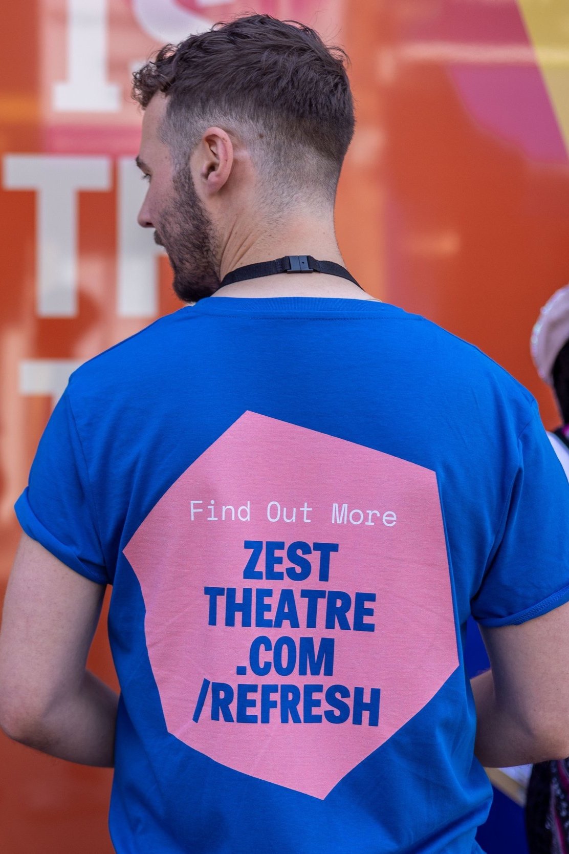 A zest member of staff wears a refresh t-shirt. The back reads ' Find Out More zesttheatre.com/refresh