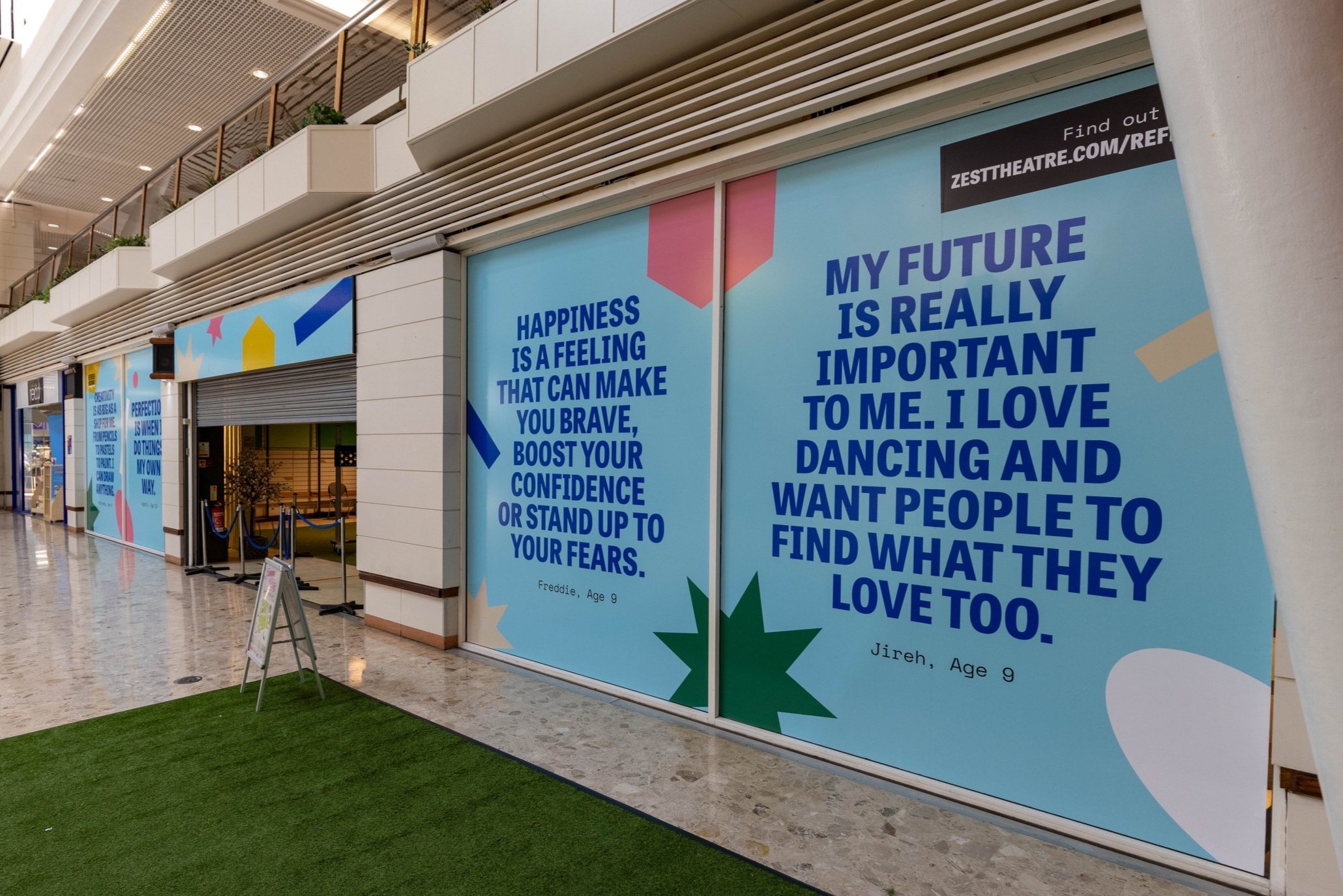 A row of light blue artworks wrapping empty shops in a shopping centre. Each feature a quote from a young person.