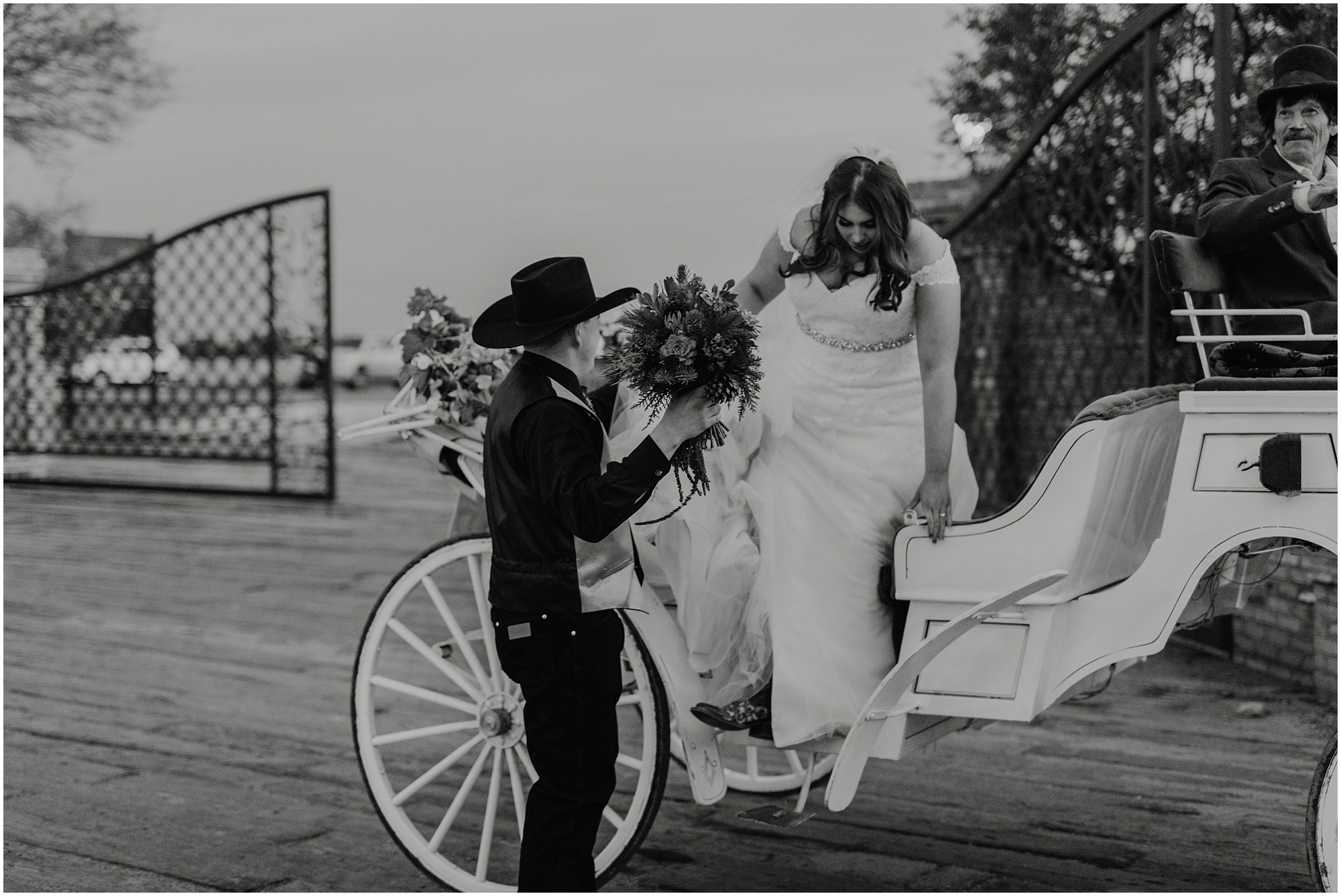 The groom helps his bride out of the horse drawn carriage after their Christmas Country Wedding.