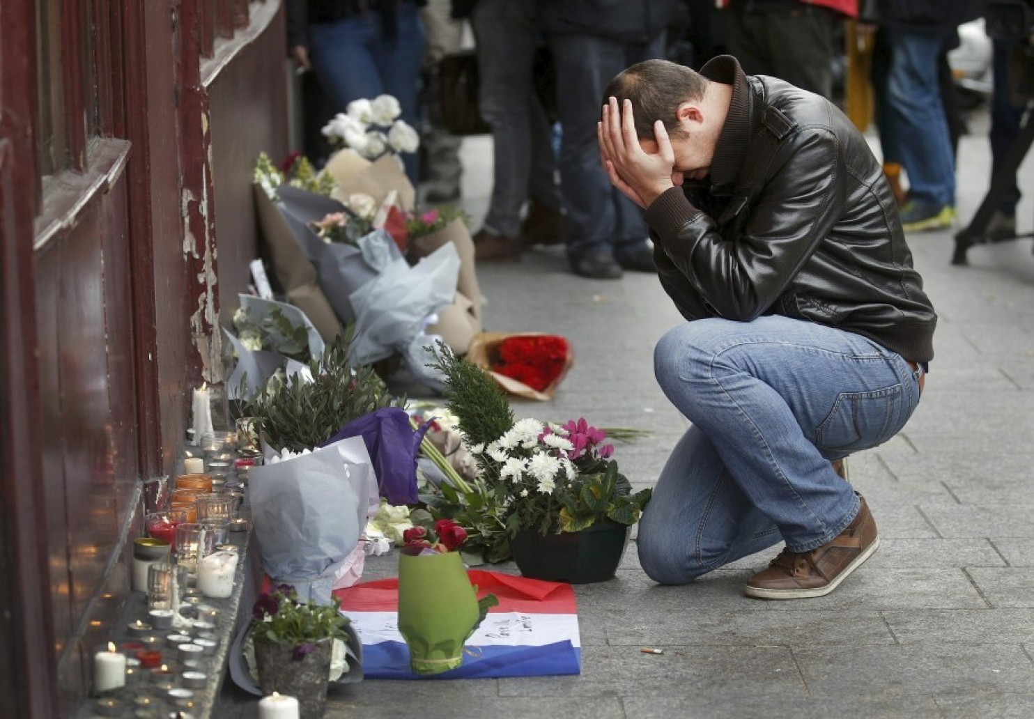 A man kneels next to a memorial outside Le Carillon restaurant the morning after a series of deadly attacks in Paris. (Christian Hartman/Reuters)