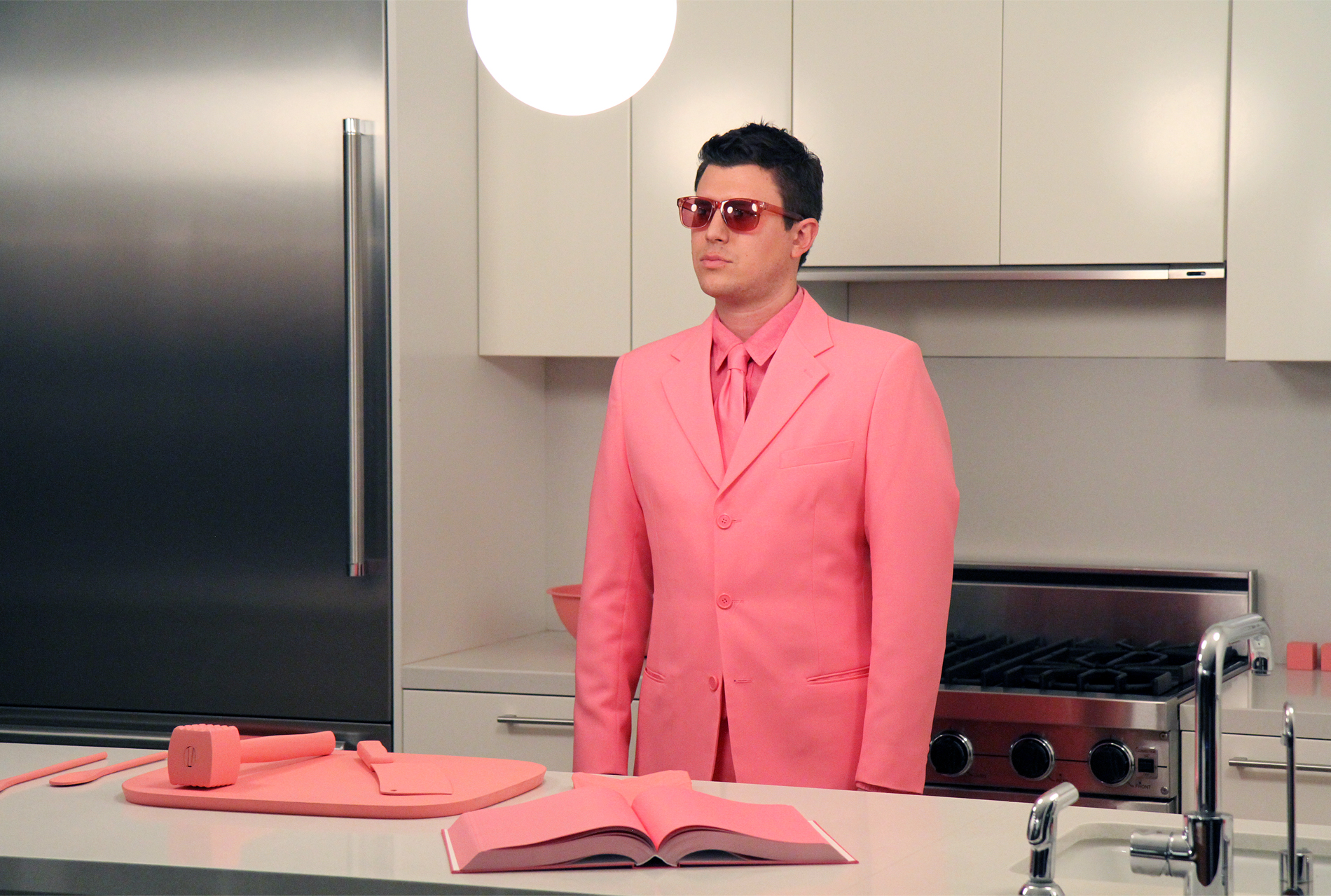   The Schauss Kitchen (Cooking)  Baker-Miller Pink painted kitchen objects, Baker-Miller Pink "cookbook," Baker-Miller Pink color therapy glasses, custom Baker-Miller Pink suit Installation dimensions variable, performance duration 15 minutes Marine 