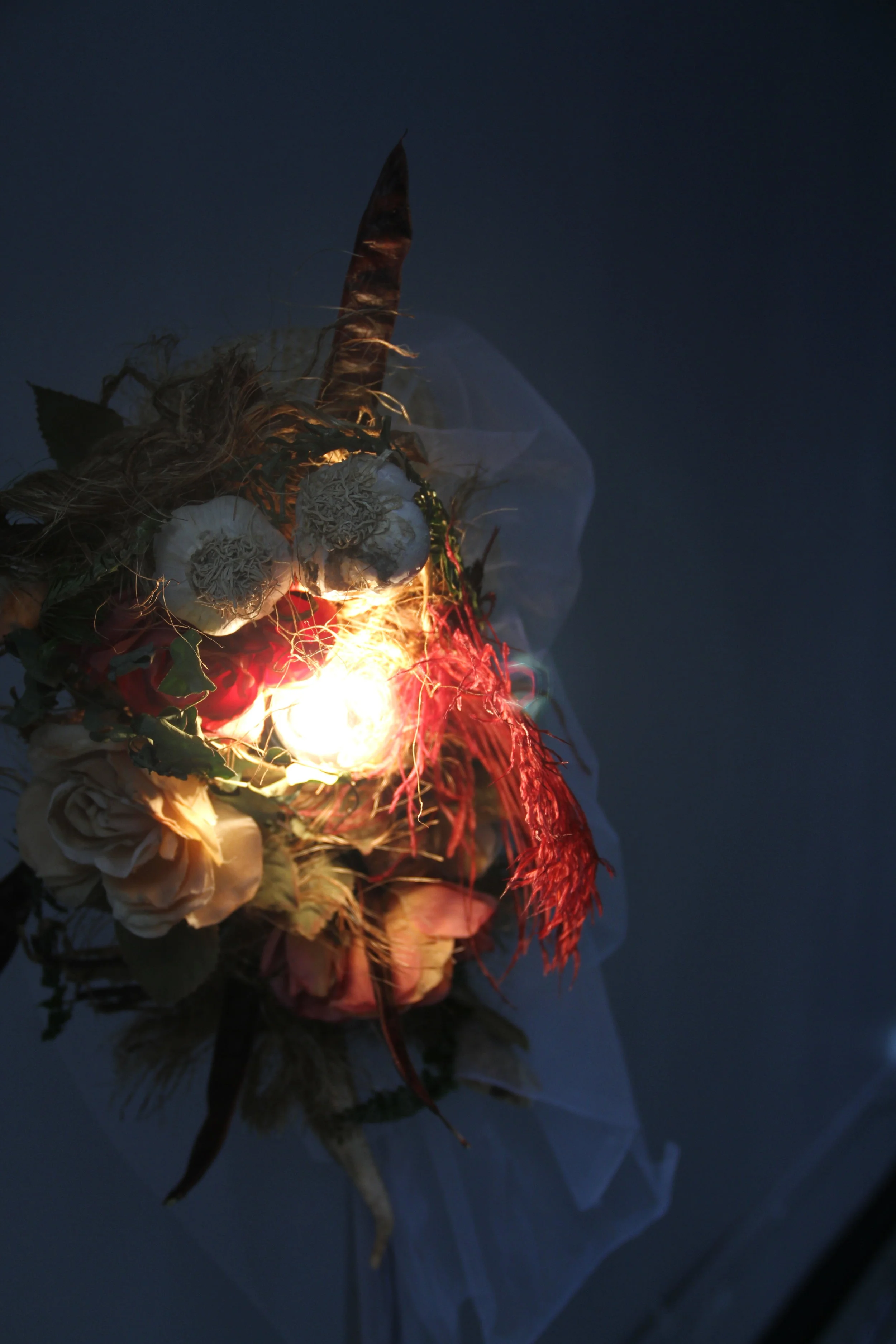  Materials: Repurposed straw hat, nylon, rope, feathers, artificial flowers, seeds, dried garlic, and wood. 