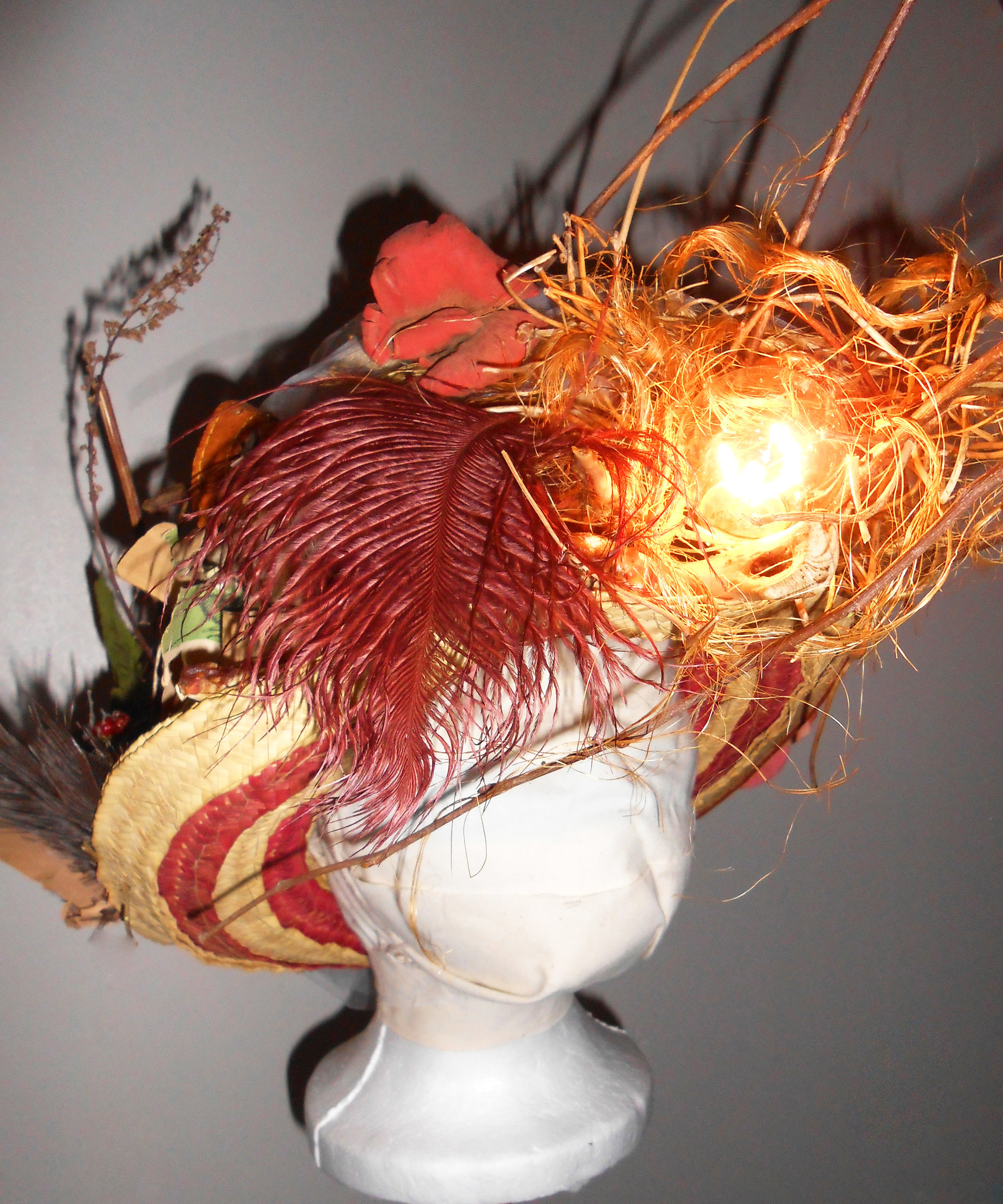 Materials: Repurposed straw hat, rope, branches, leafs, artificial flowers, popurri, feathers, turkey bones, newspaper, cardboard, dry acrylic paint, leather belt, and tulle.