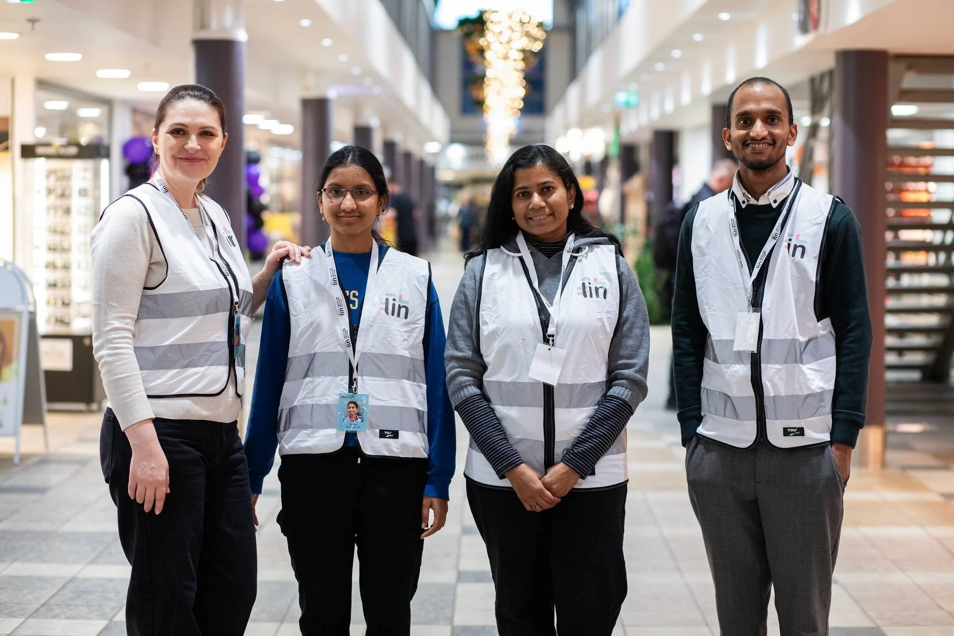 Fire frivillige i hvit refleksvest som det står "LIN" på.