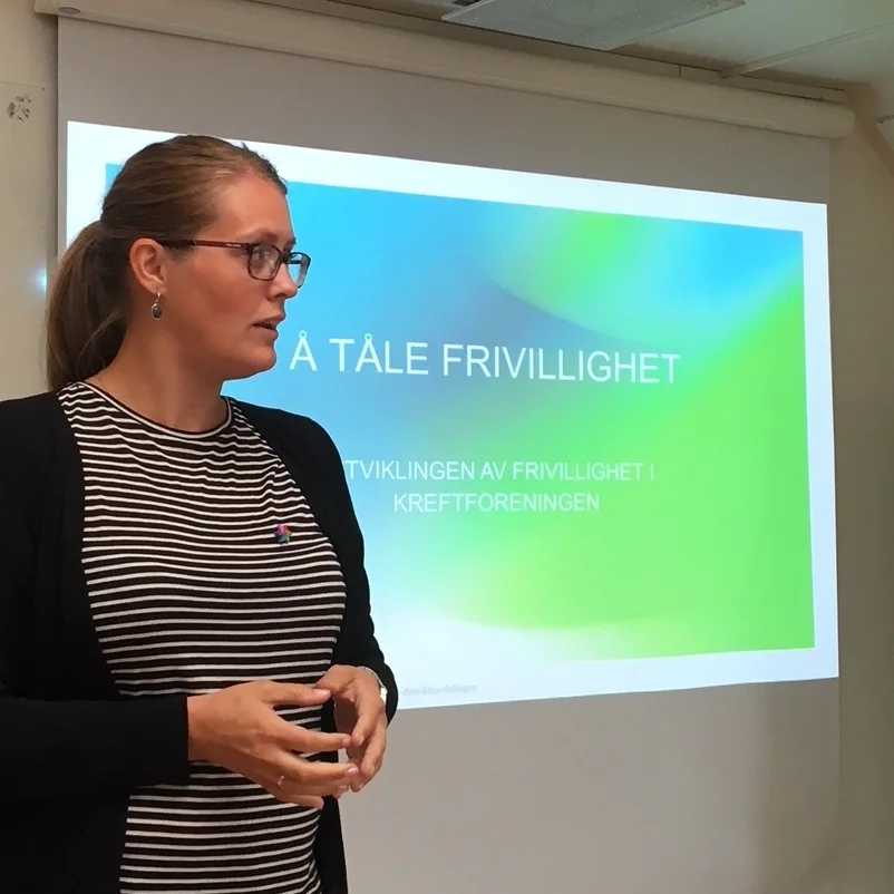 dame i stripete skjorte prater ved et lerret