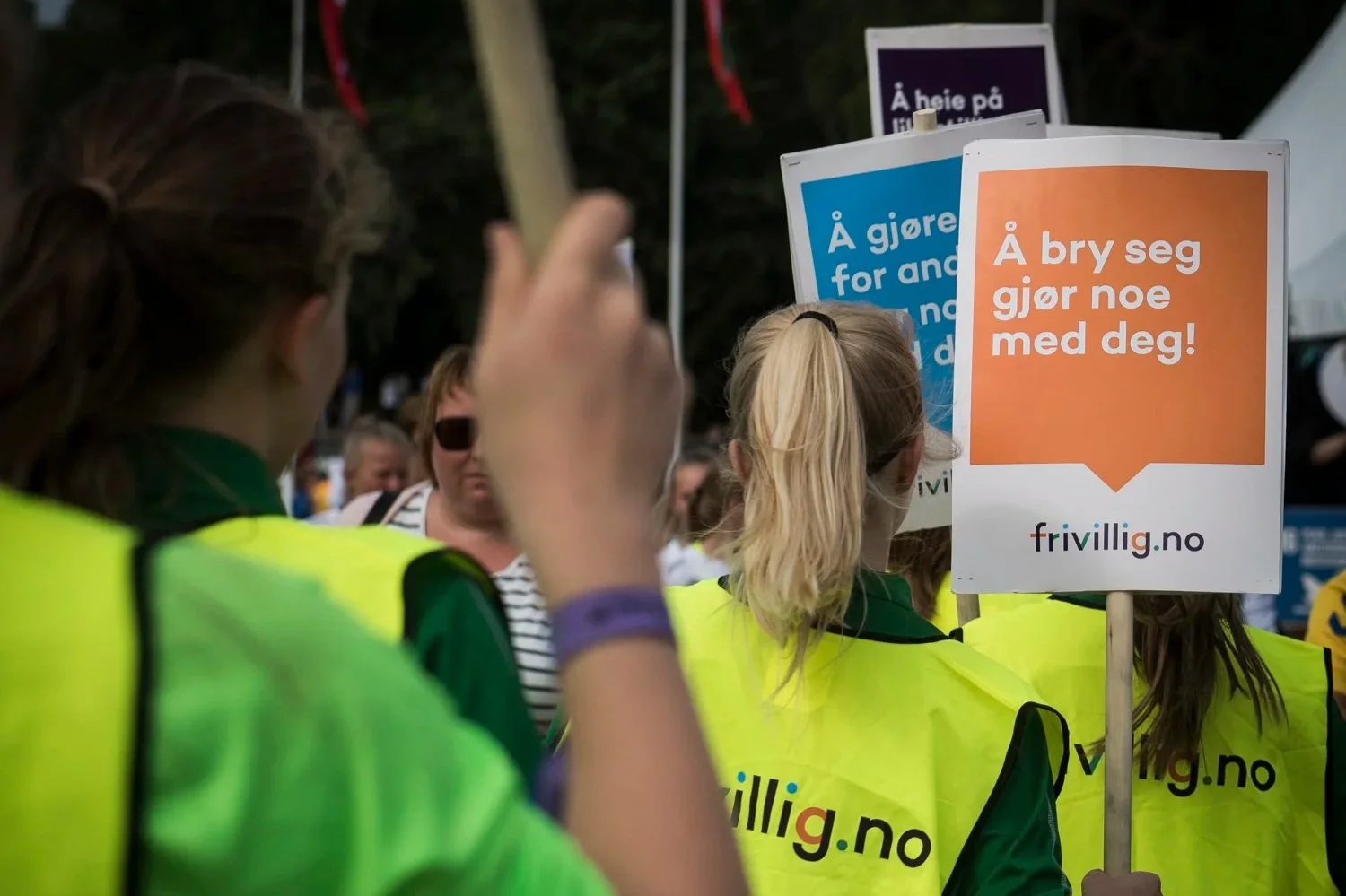 personer i refleksvest bærer plakater med frivillig.no sin logo
