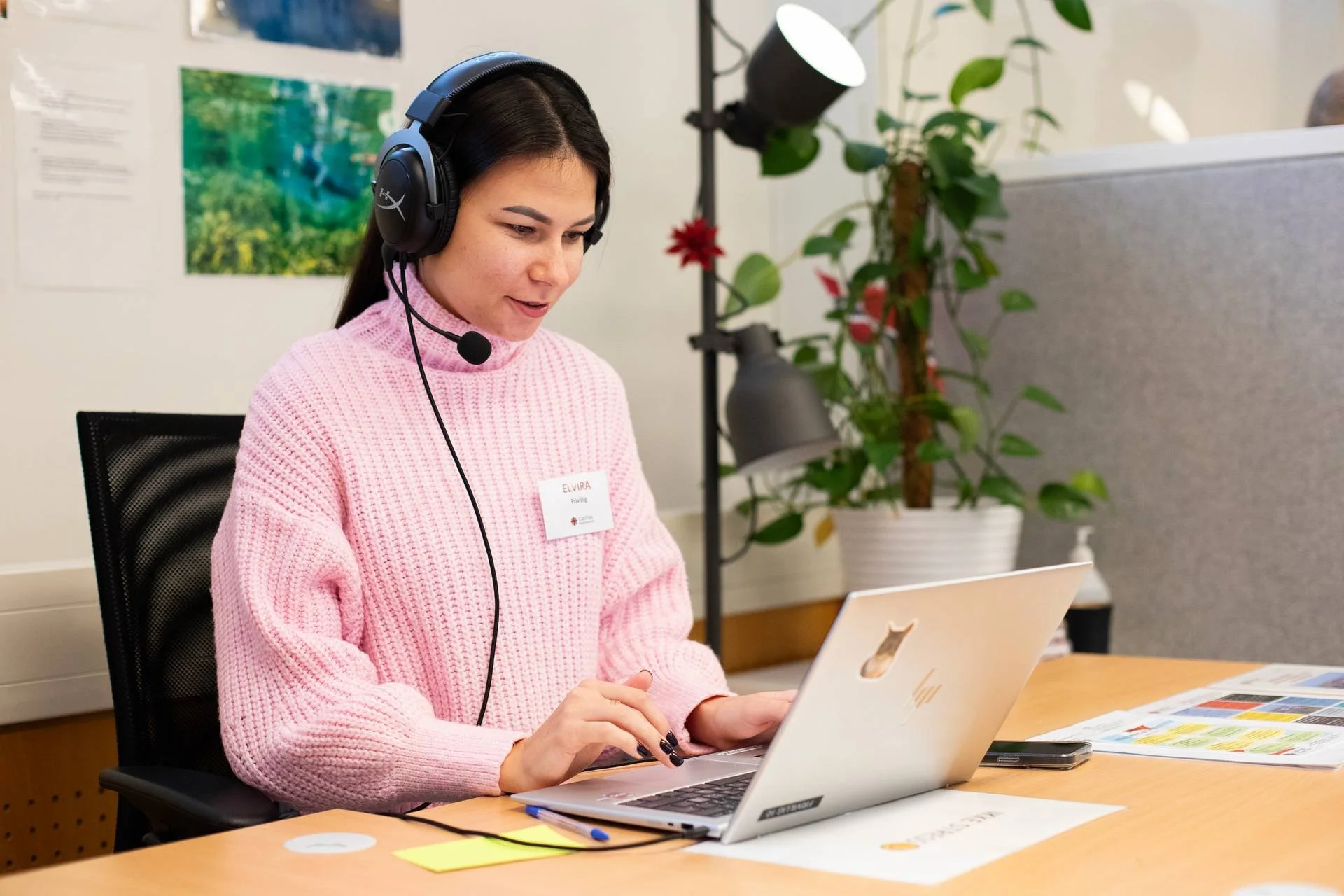 dame i rosa genser sitter og jobber på en pc
