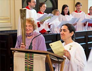 Mary Braybrooke holds a golden Olympic torch during the Golden Rule service.