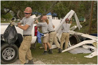 Volunteers from AmeriCorp, a government-funded agency, pile debris from a yard into their truck to take to a pick-up location. – Photo: Wikipedia, Marvin Nauman/FEMA