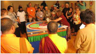 Tibetan Buddhist Lori Petruskevich guides the hands of a local interfaith leader as the dissolution of the beautiful Mandala of Compassion begins at the end of the Connect.