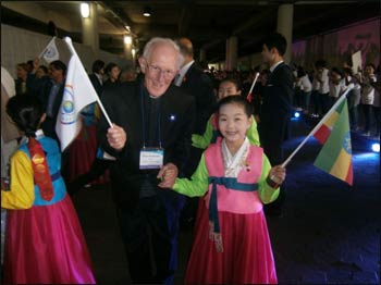 Marcus takes the hand of a South Korean girl at the Peace Summit