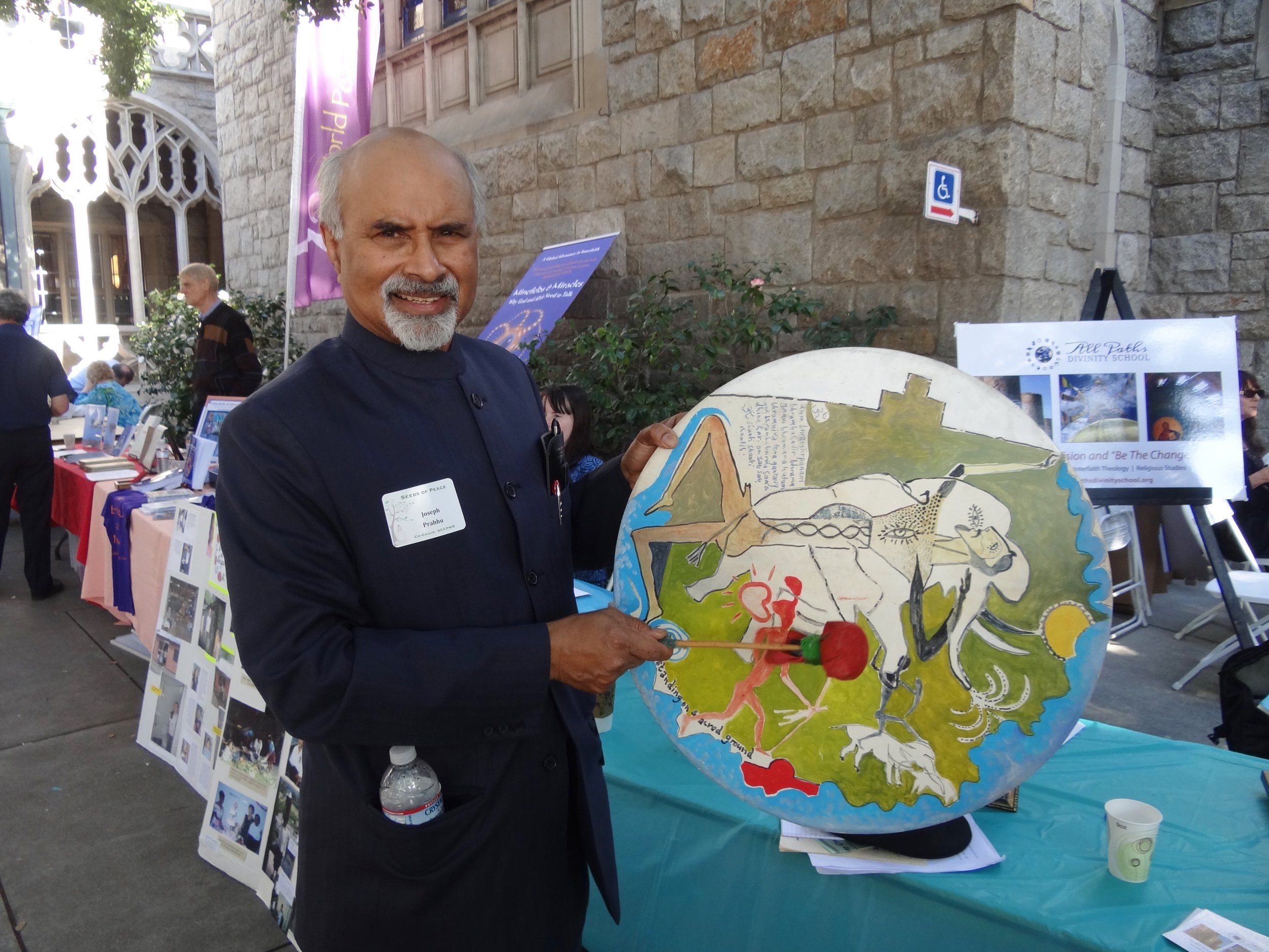Professor Prahbu holding a "Mankind" initiation drum, painted by artist Andre van Zijl, at a Seeds for Peace conference in Pasadena, California, sponsored by the Southern California Council of the Parliament of the World’s Religions. – Photo: Ruth Broyde Sharone