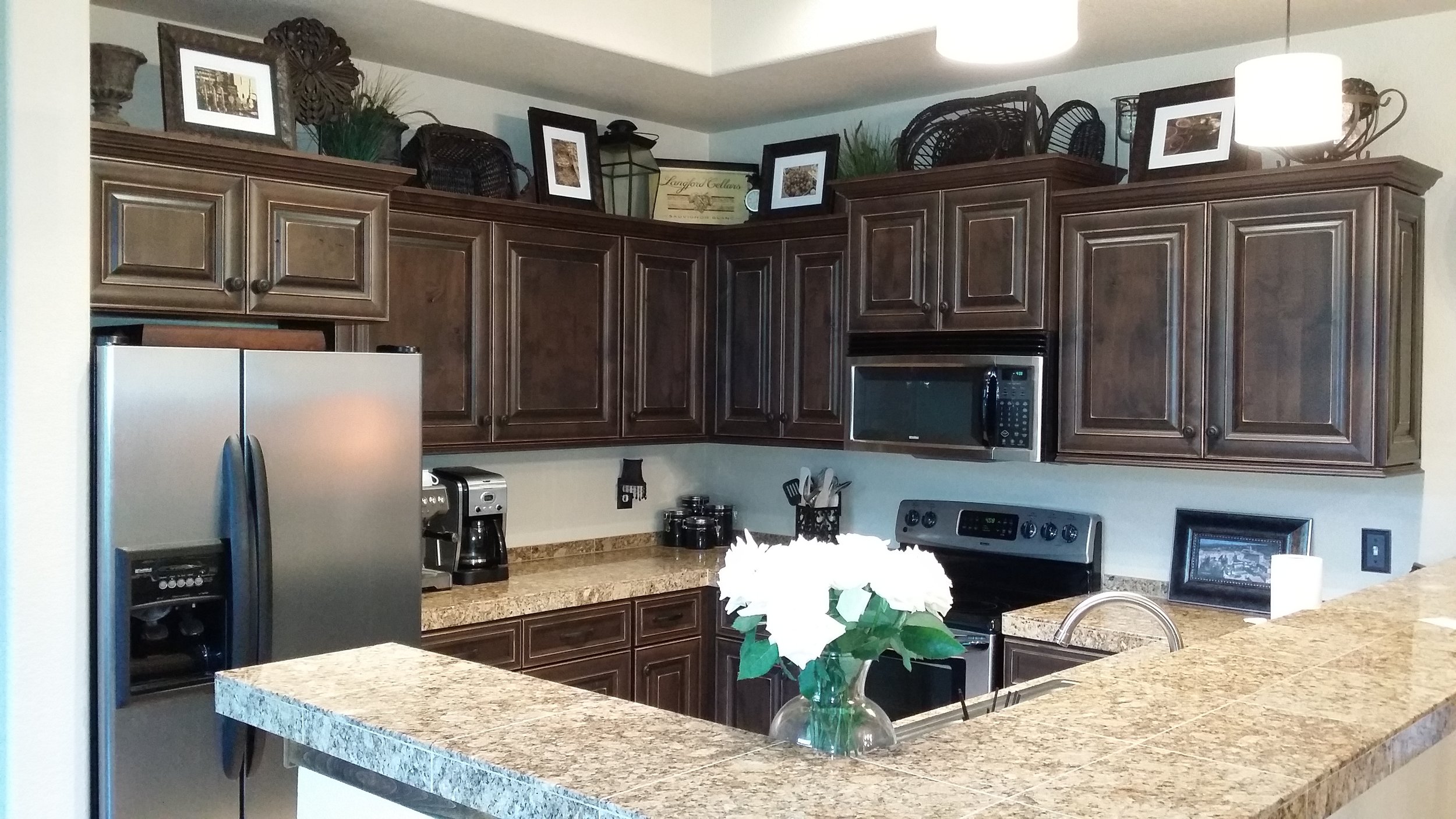 This traditional craftsman style kitchen features over sized micro and fridge cabinets with crown moulding and under cabinet trim. It also has full overlay spacing and a rub through finish.