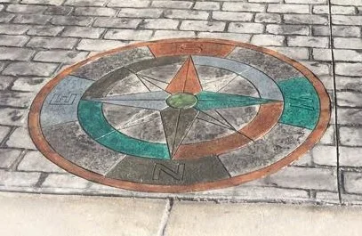 This expansive stamped driveway utilized the UK Cobblestone stamp pattern with Light Gray color highlighted by the Antique process. The Compass medallion was hand painted with Smokey Blue and Desert Tan.