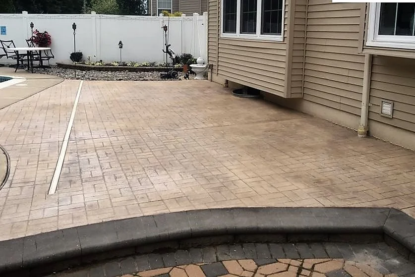 A pool surround; we removed the pavers, corrected the pitch, doweled into the foundation to alleviate the possibility of sinking and separation, then formed area to receive new 4,000 PSI concrete. Our color and stamp palette was Adobe Buff base complimented with Light Gray highlights and the Ashlar Slate stamp pattern.