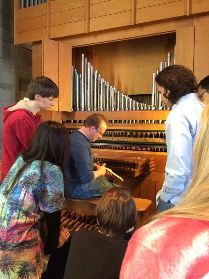 Students learn from a pipe organ builder. 