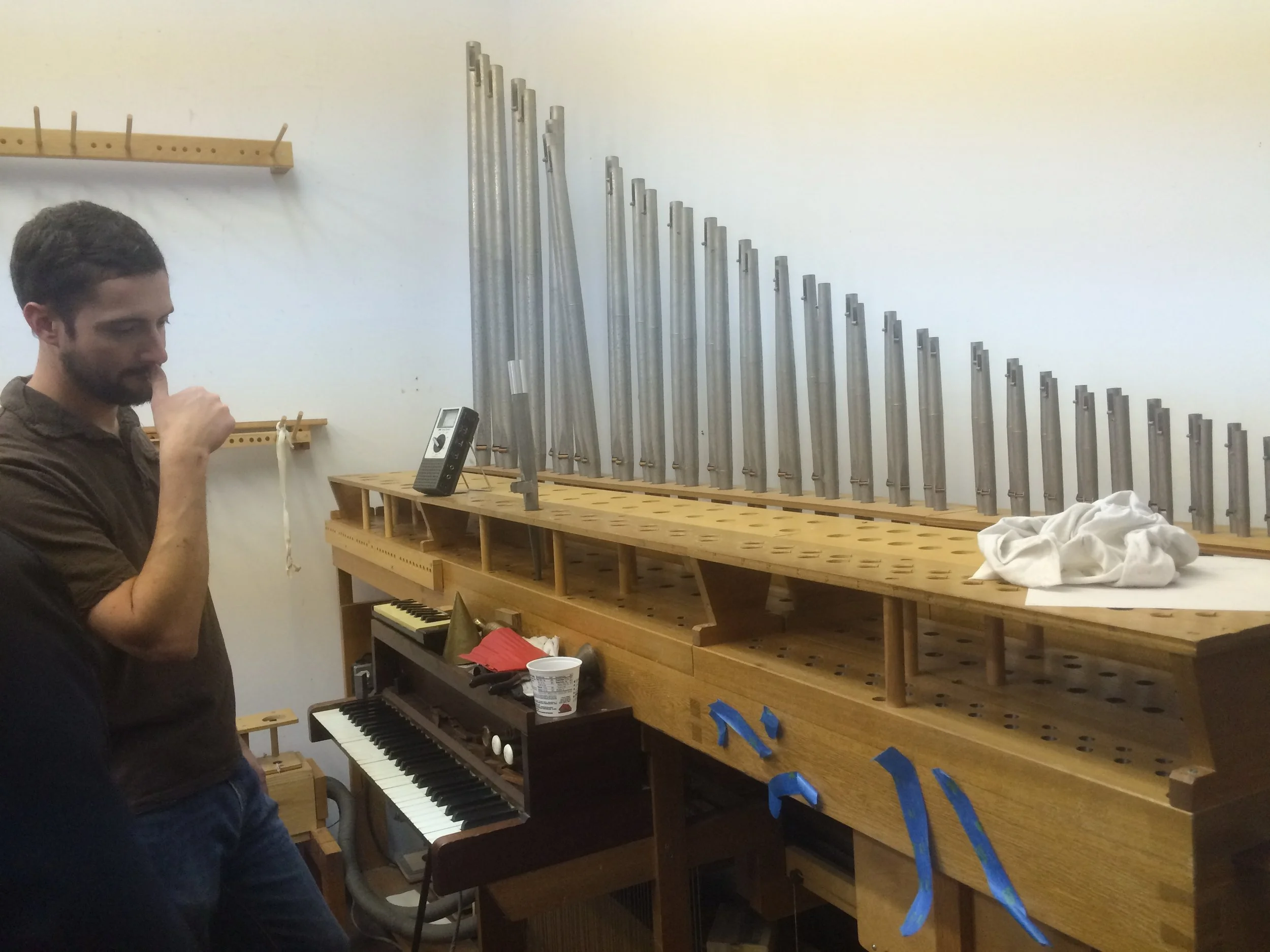 A room where pipes are refined and tested. The contraption blows wind through the pipes, and there is a bench behind Ryan where tools can be used to tinker with the pipes.