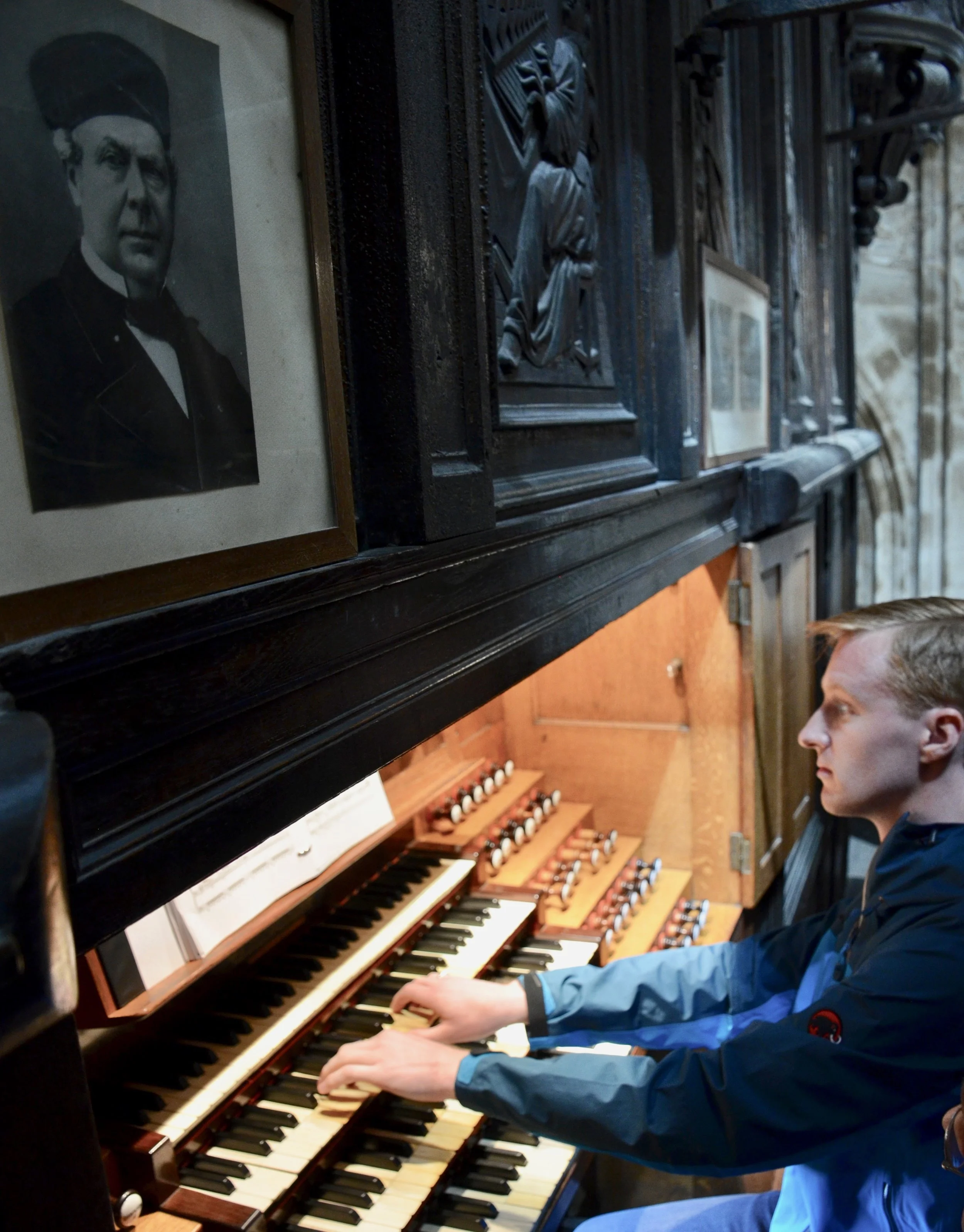 Jon Ortloff, organ builder, performing Widor. under a photo of Aristide Cavaillé-Coll in Rouen