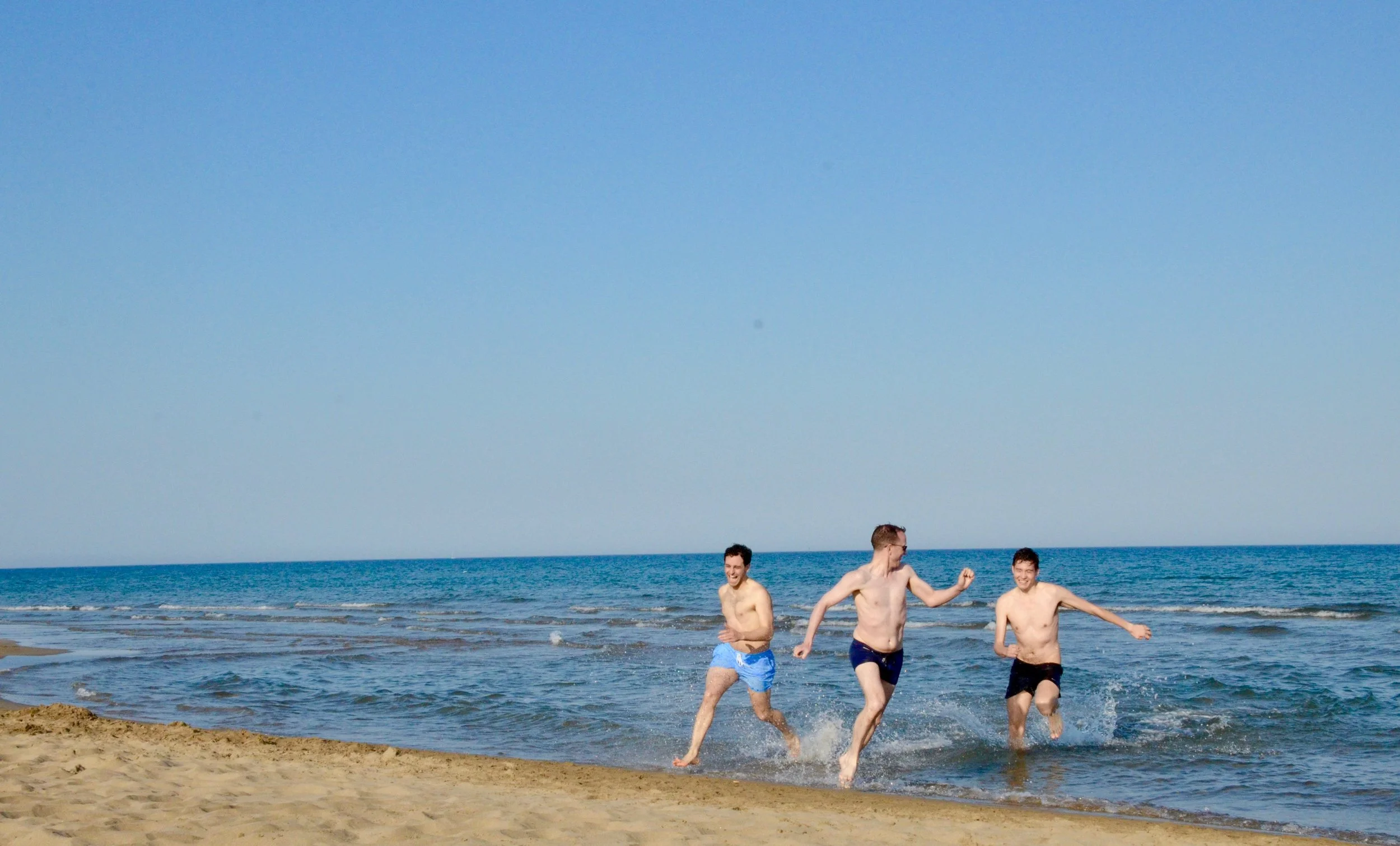 Gianmarco, Chris, and Noel playing tag on the beach.