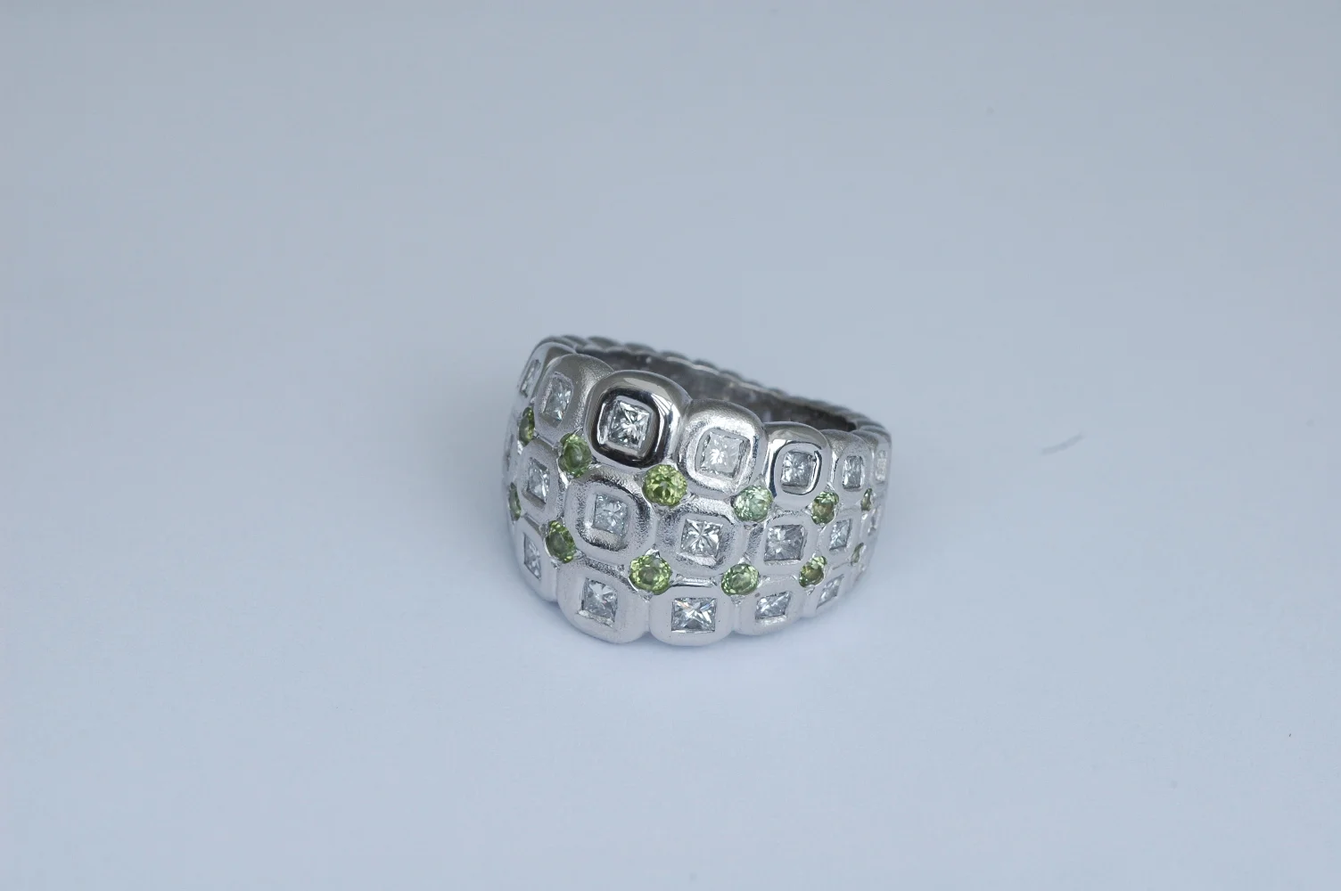 18 karat white gold ring with square princess cut diamonds and round peridots
