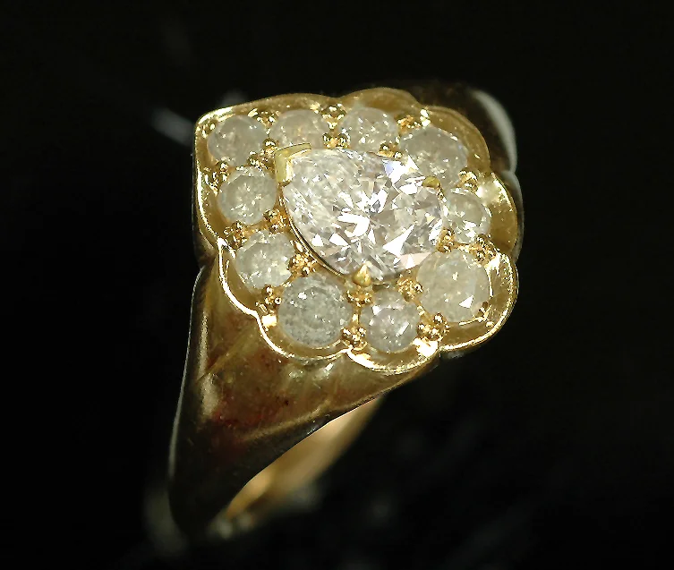 Engagement Ring in !8 karat yellow gold, set with small opaque white diamonds, and a center pear shaped diamond.