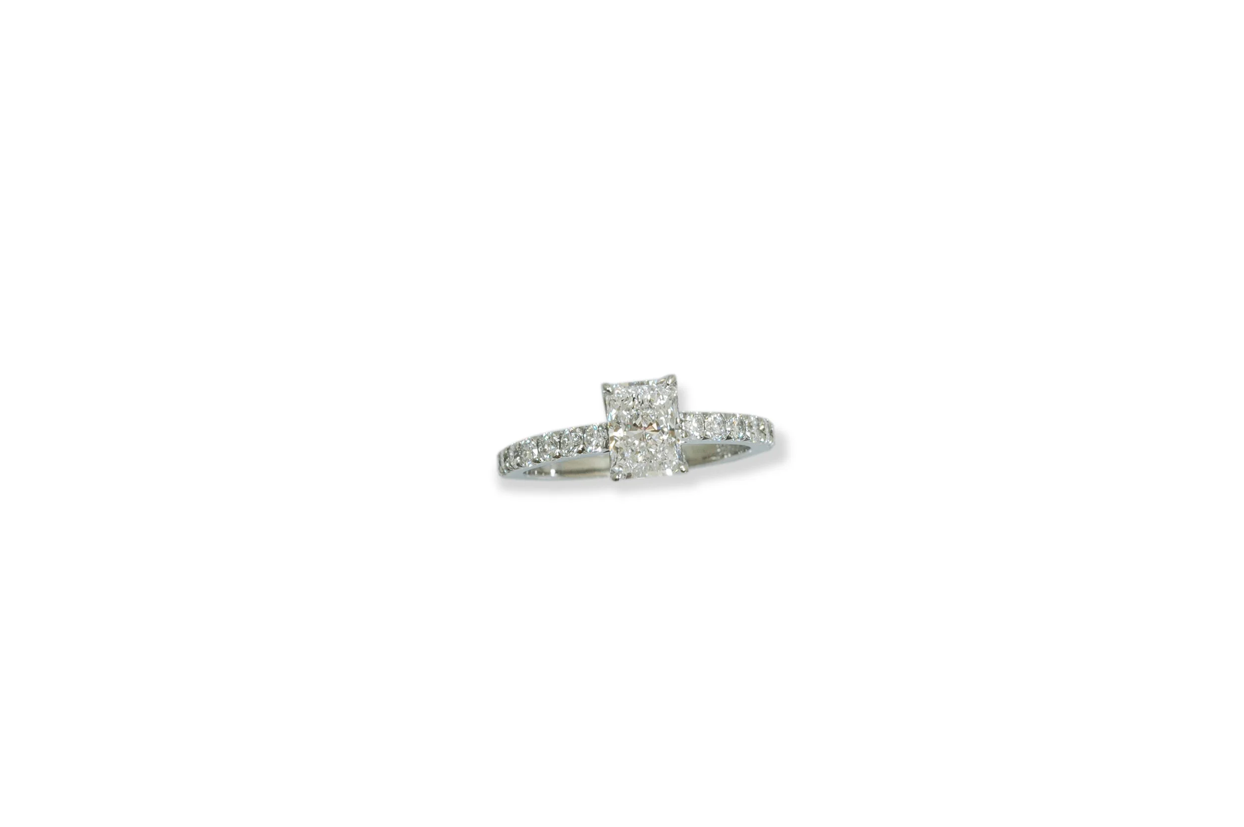 Engagement ring in platinum with a radiant cut Diamond in the center and brilliant cut diamonds on the band.