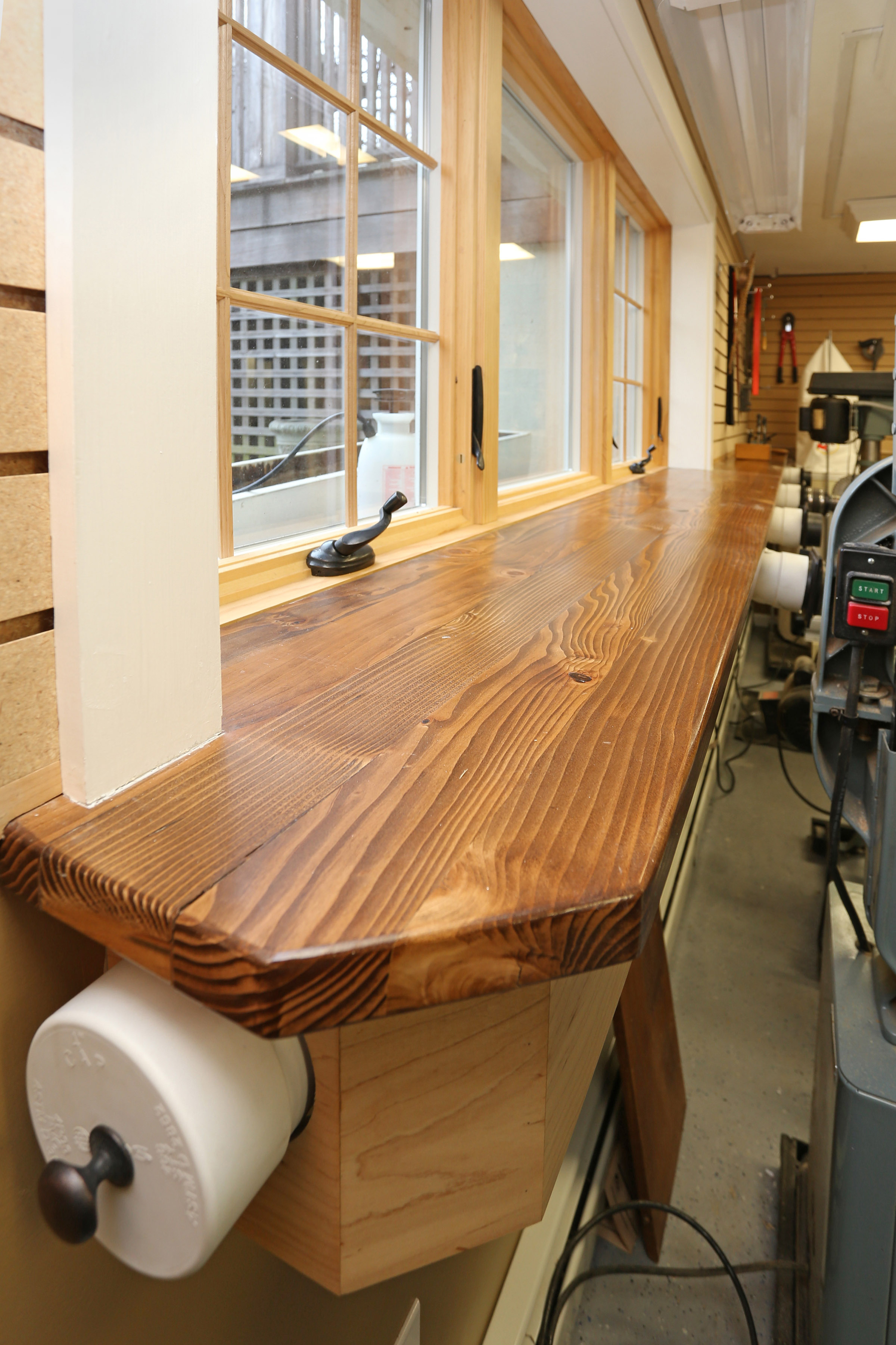  The dust vacuum system is housed beneath the long custom countertop by the window. The end cap of the system is removable to attach a vacuum hose for cleaning the shop floor. 