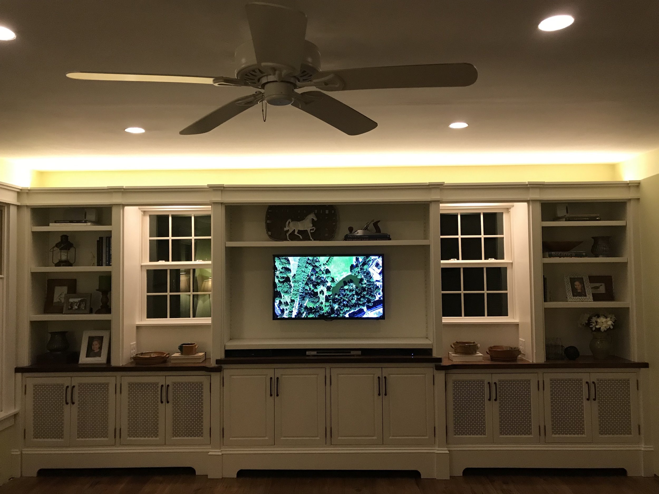  Instead of doing more traditional crown molding, we decided not to build the upper units to the ceiling so that we could carry the existing window trim across the top as a design detail. This allowed us to add another hidden feature: a long strip of