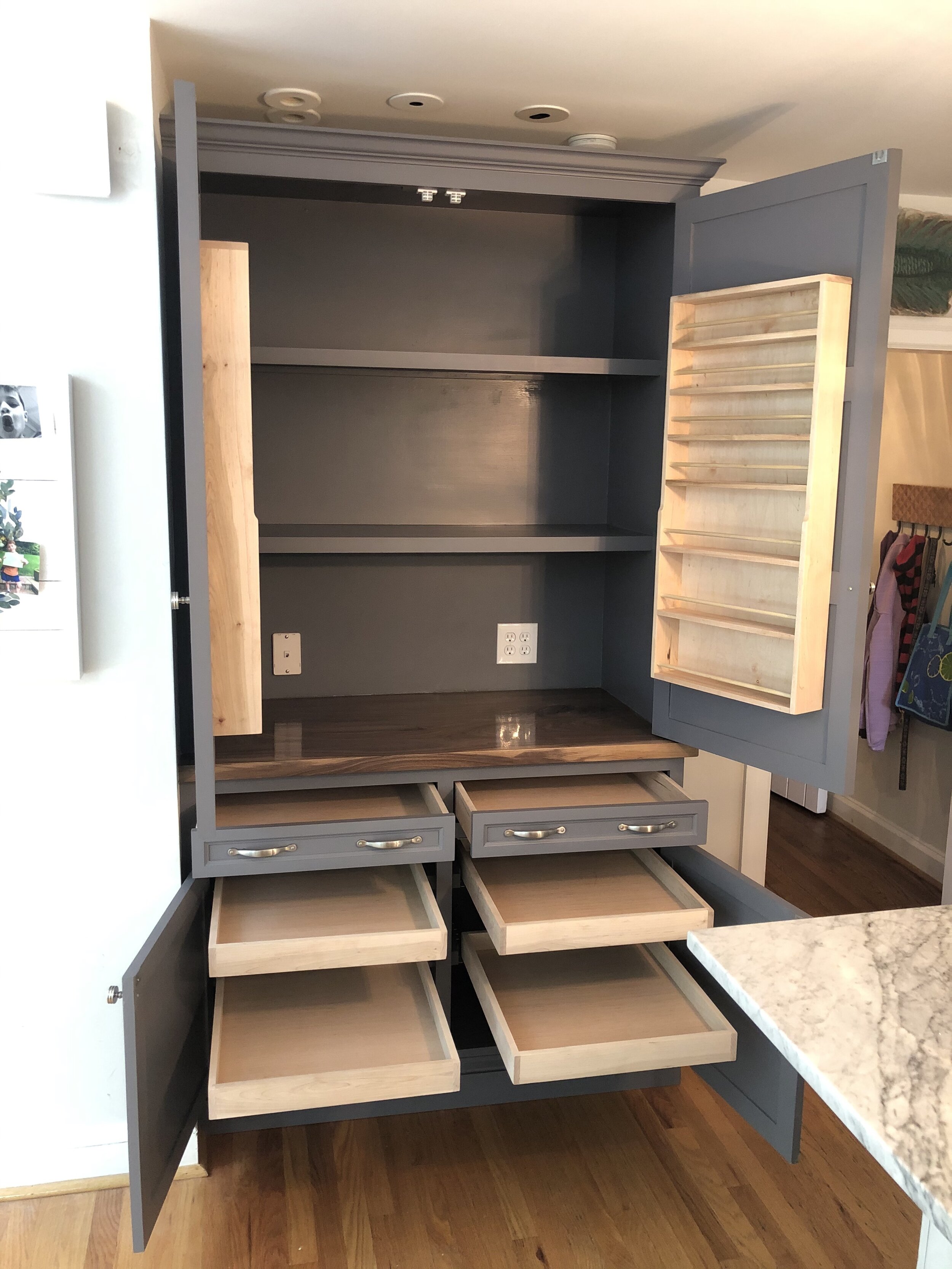  The lower cabinet has two standard drawers and four pull-out shelves. The upper cabinet sits atop a solid black walnut countertop and has several shelves for additional storage and spice racks attached to each door.  